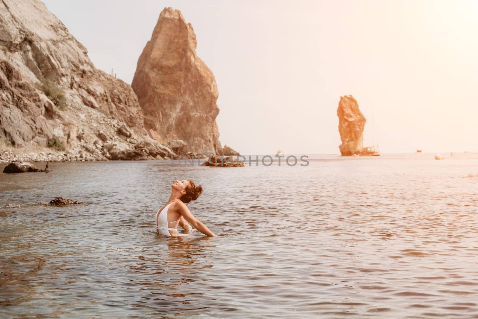 Woman sea fitness. Happy woman in a white bikini performing pilates in the sea on the beach. Female fitness yoga routine concept. Healthy lifestyle. by panophotograph