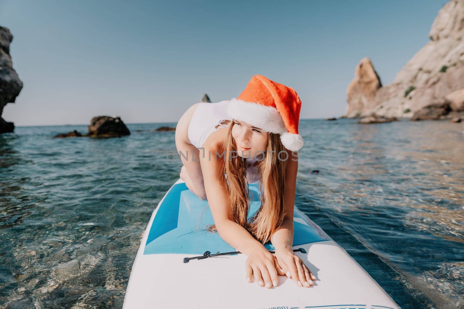 Close up shot of happy young caucasian woman looking at camera and smiling. Cute woman portrait in bikini posing on a volcanic rock high above the sea