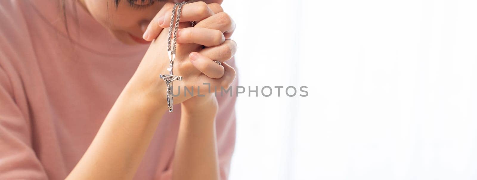 Close-up female folded hand prayed on holy bible book faithfully at wooden church. Concept of hope, religion, faith, christianity, catholic, believe and god blessing. Blurred background. Burgeoning.