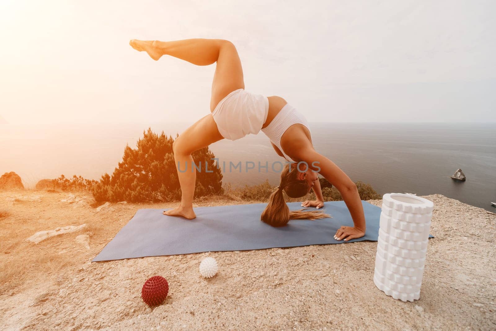 Woman sea pilates. Sporty happy middle-aged woman practices pilates on a beach near the sea, promoting a healthy lifestyle through outdoor fitness and meditation. by panophotograph