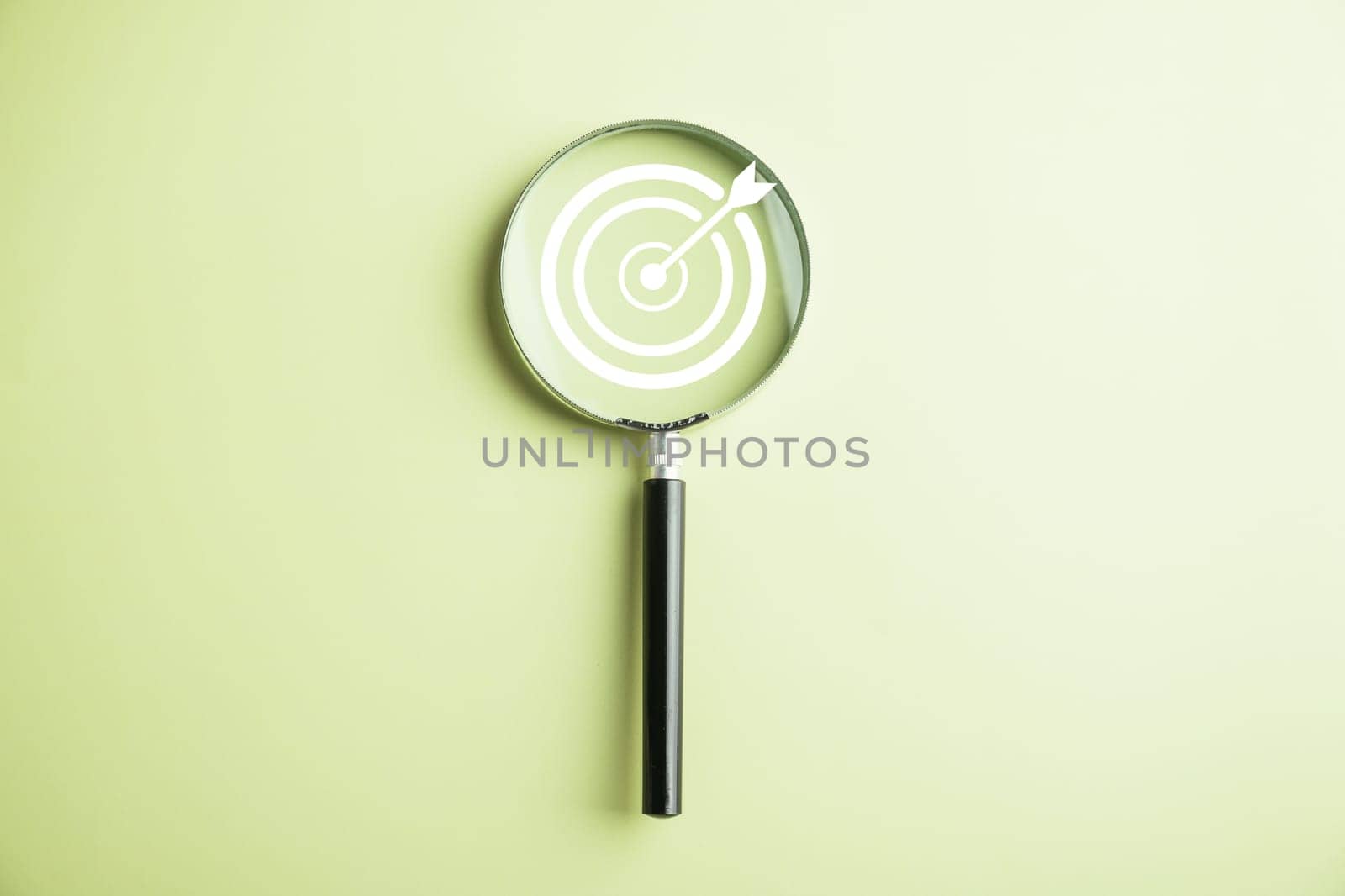 Features a target board captured inside a magnifier glass, illustrating the focus on business objectives, target search concept, and attaining success. Isolated on a background with copy space.