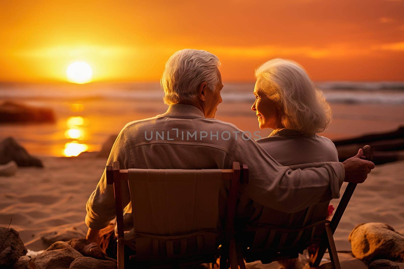 Happy retired couple relaxing on sun loungers near the seashore at sunset. High quality photo