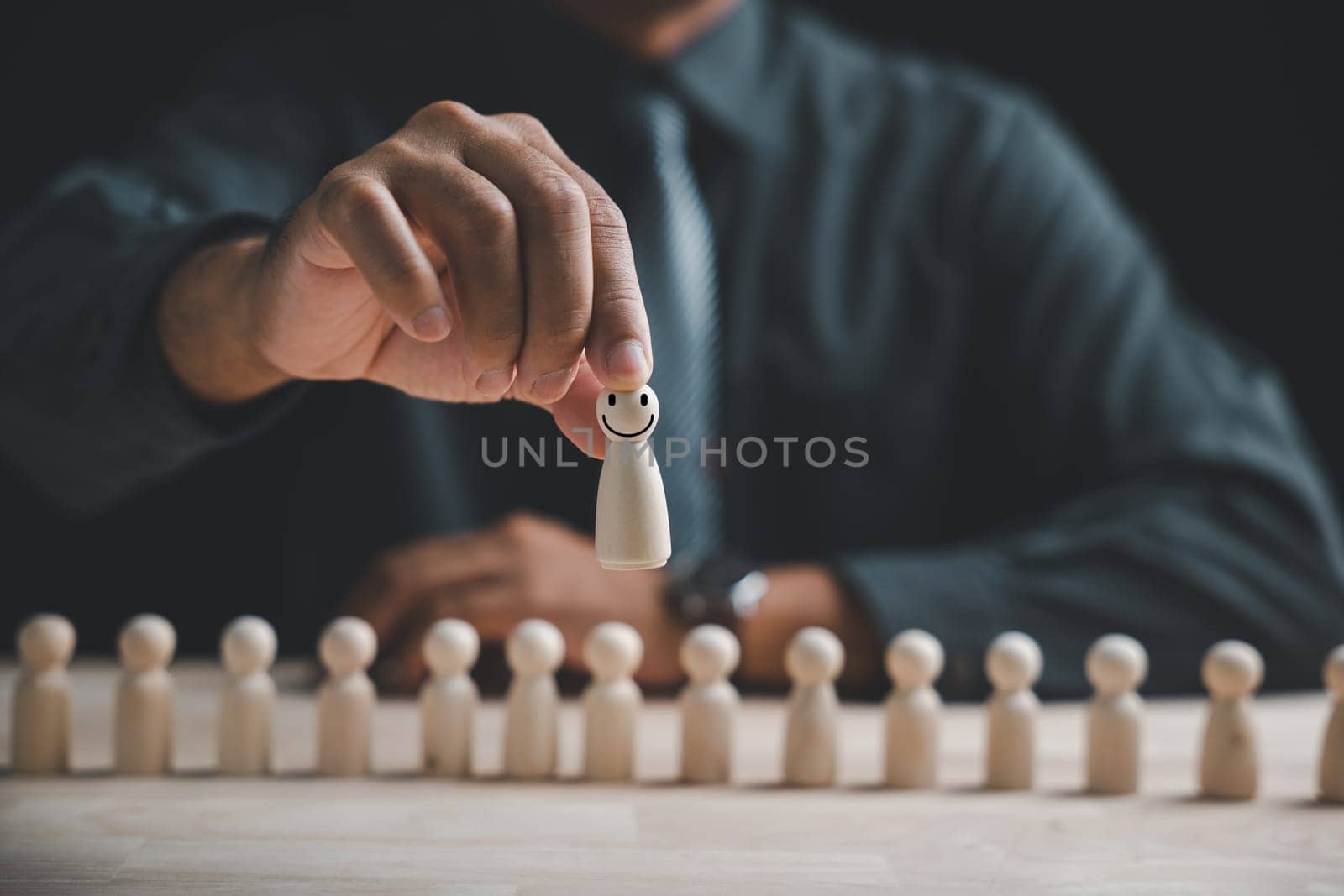 Wooden human figure held by man hand. HR officer looks for leader and CEO. Leader breaks free from the crowd. Personal development, motivation, challenge. HR, HRM, HRD concepts.