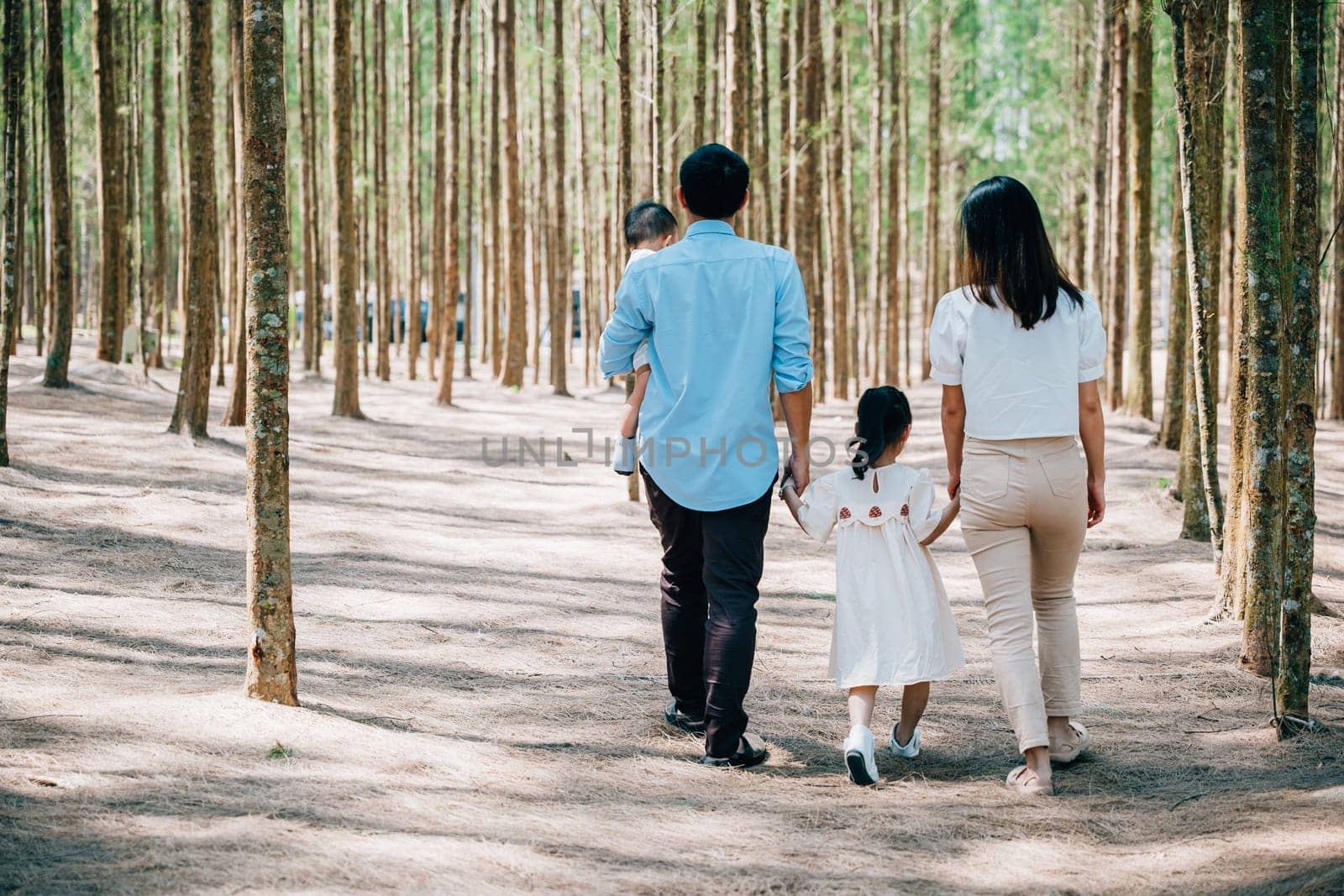 Happy family walking through the sunny forest by Sorapop