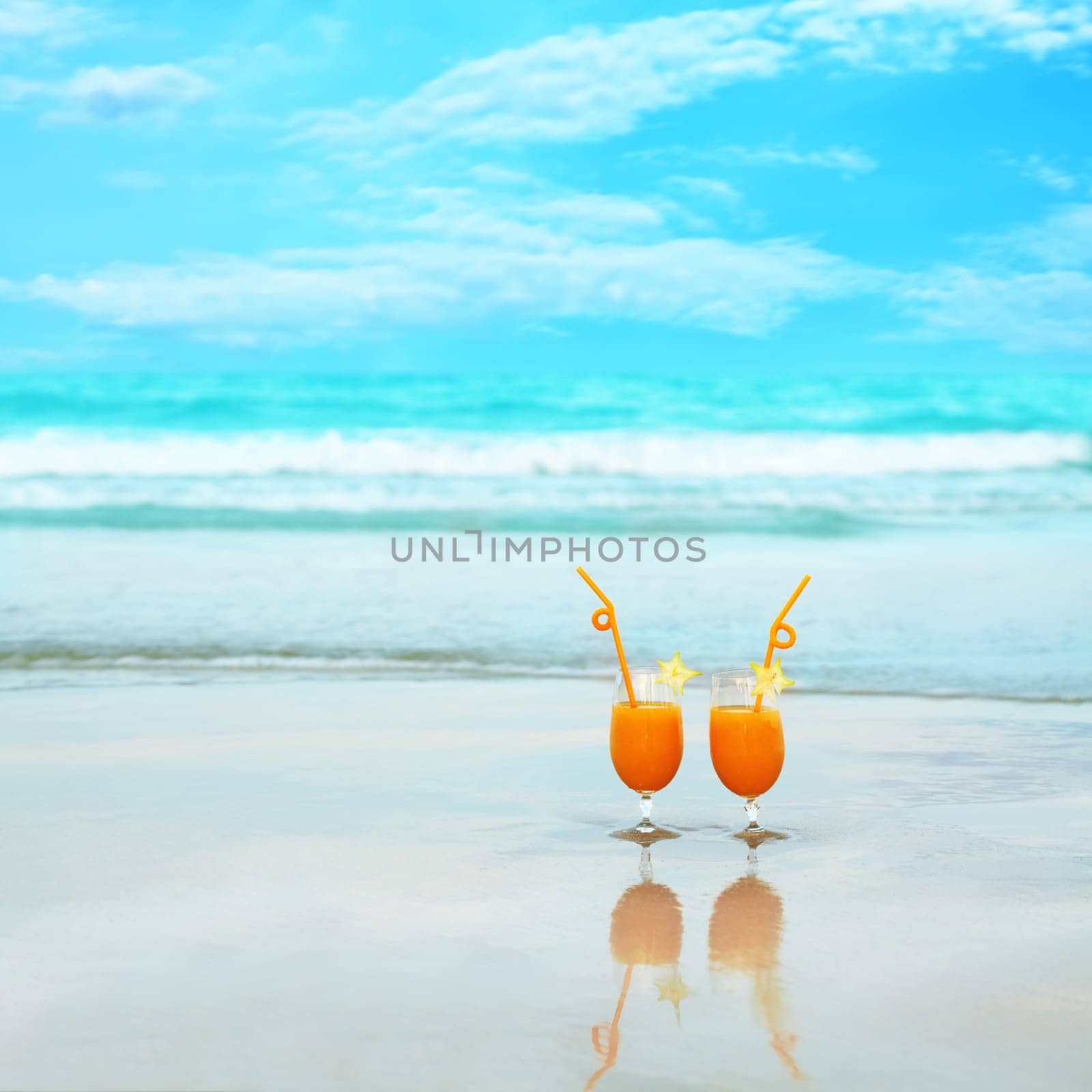 Two glasses of orange juice on tropical beach