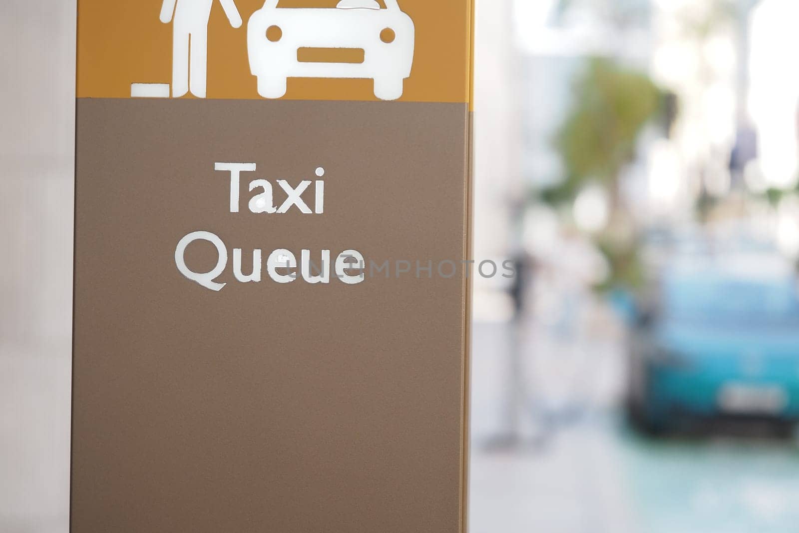 A sign indicating the taxi queue at a bustling city location during the day.