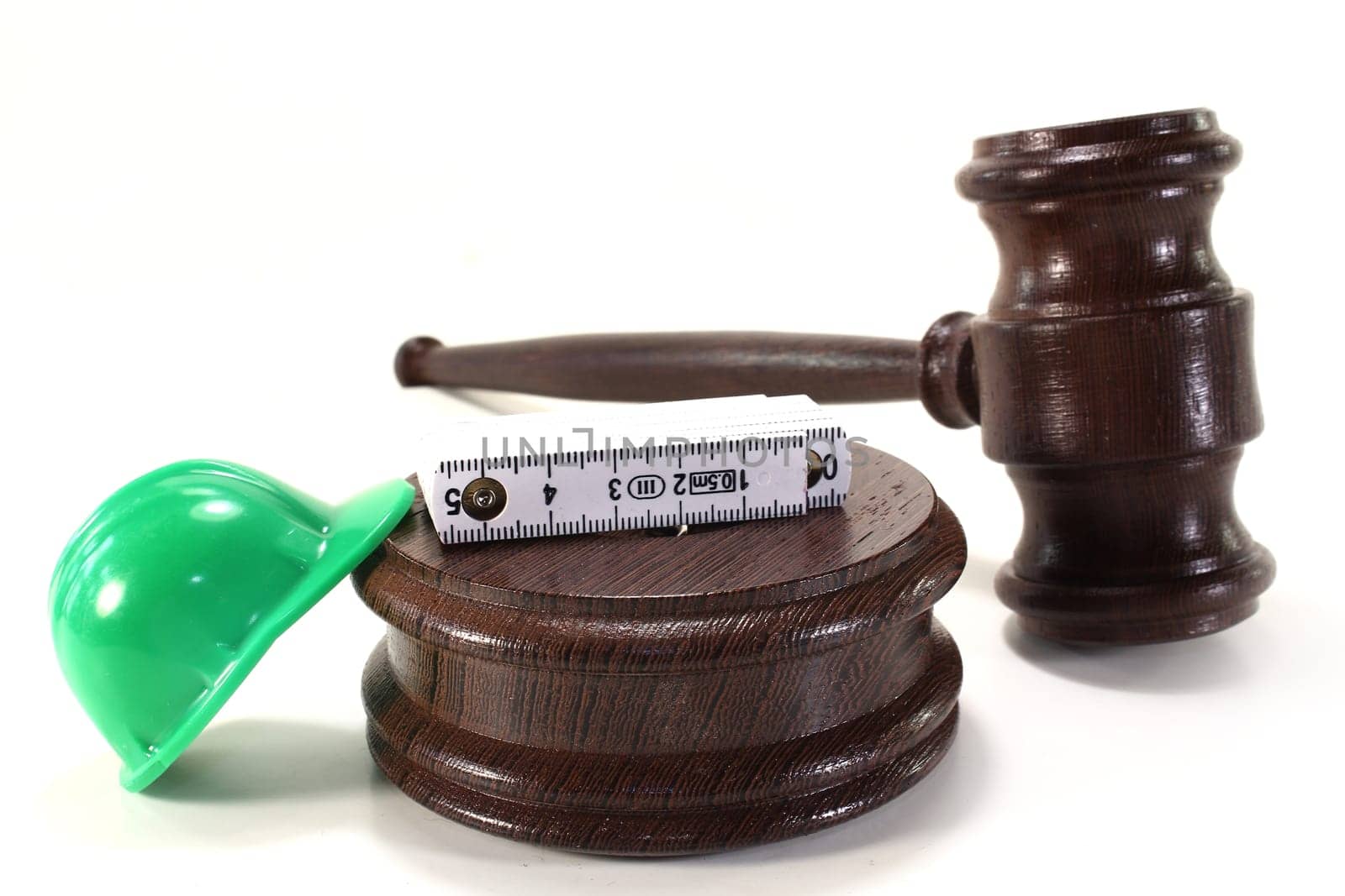 Judge's gavel with construction helmet and folding rule against light background