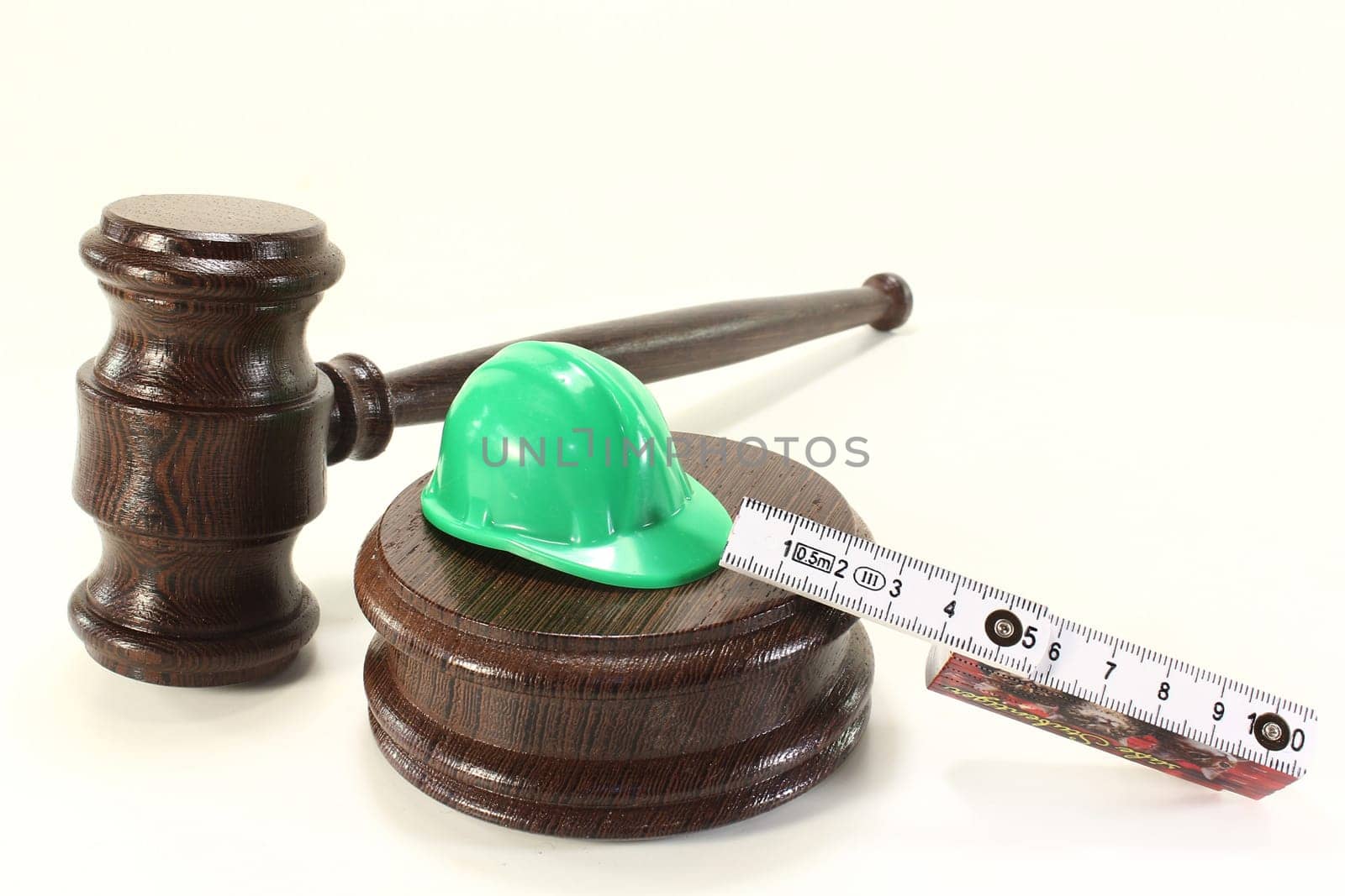 Judge's gavel with construction helmet and folding rule against light background