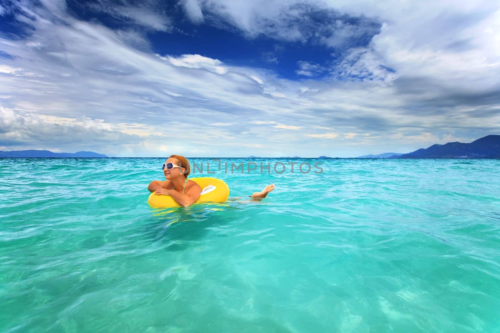 Woman swimming with yellow tube in the sea