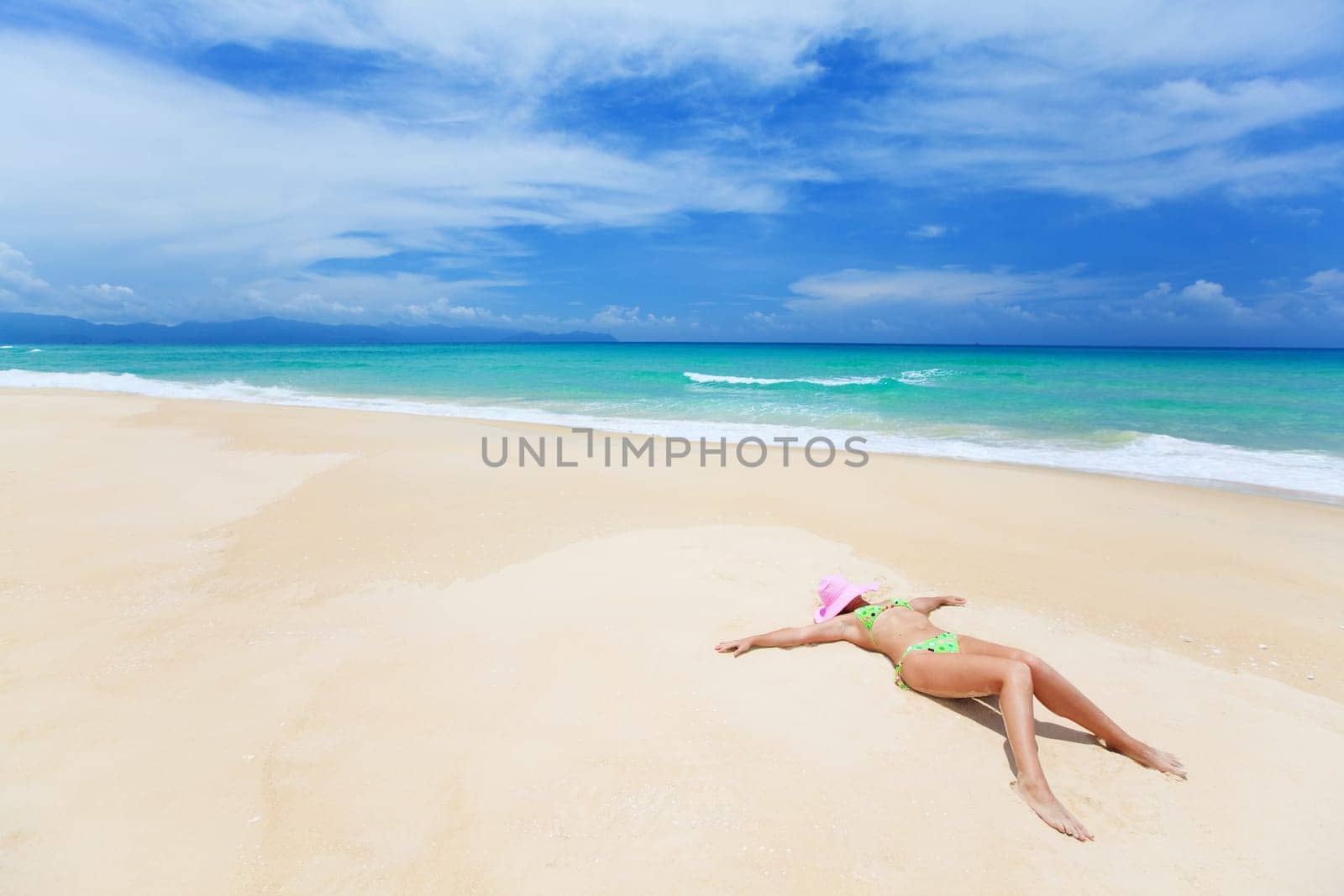 Woman in pink hat lies on the beach
