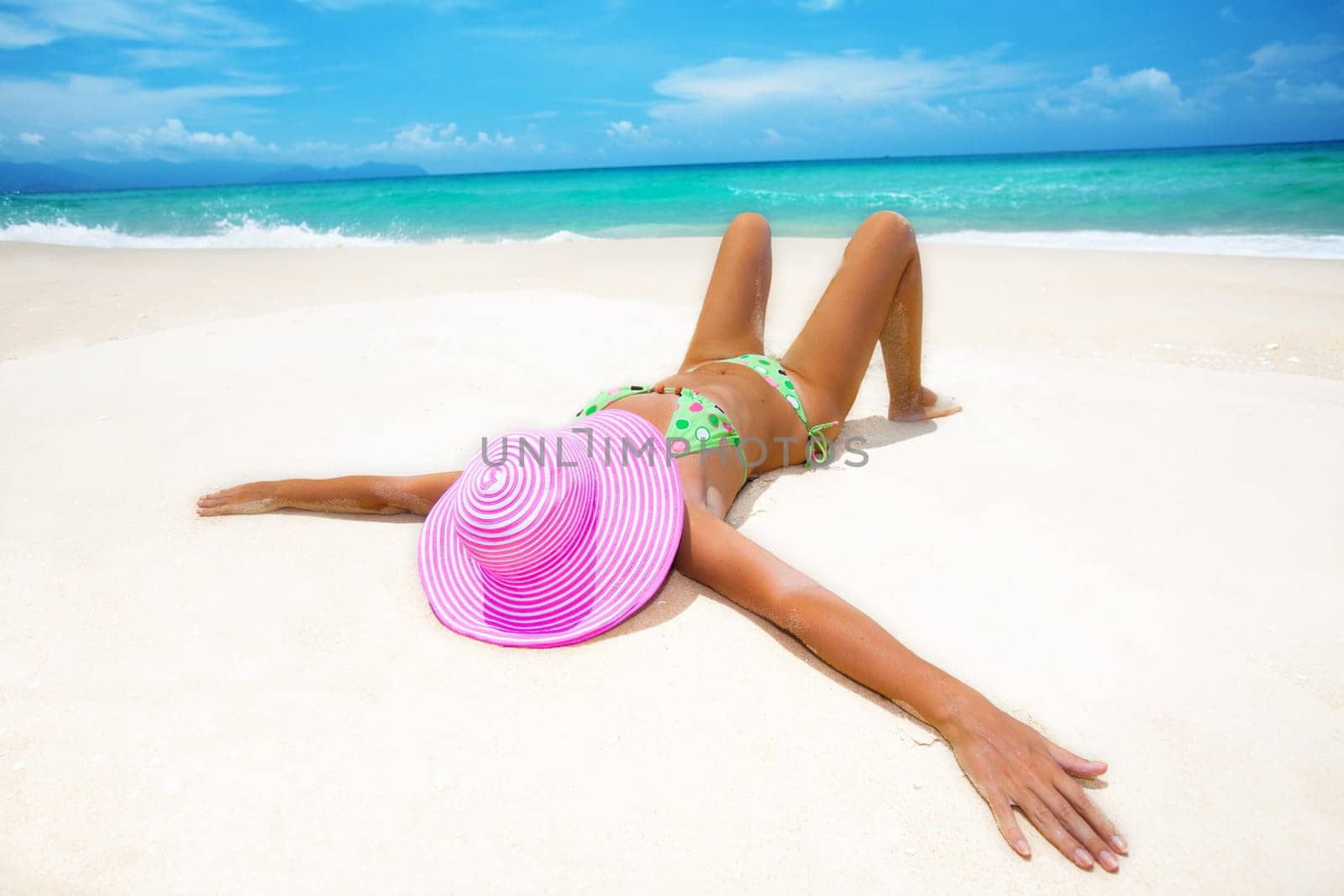 Woman in pink hat lies on the beach