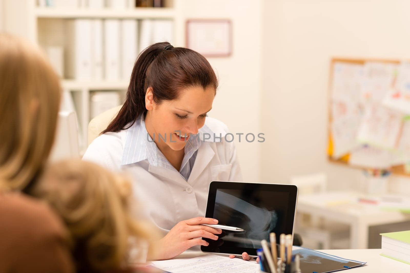 Female pediatrician showing bone X-ray on tablet medical office