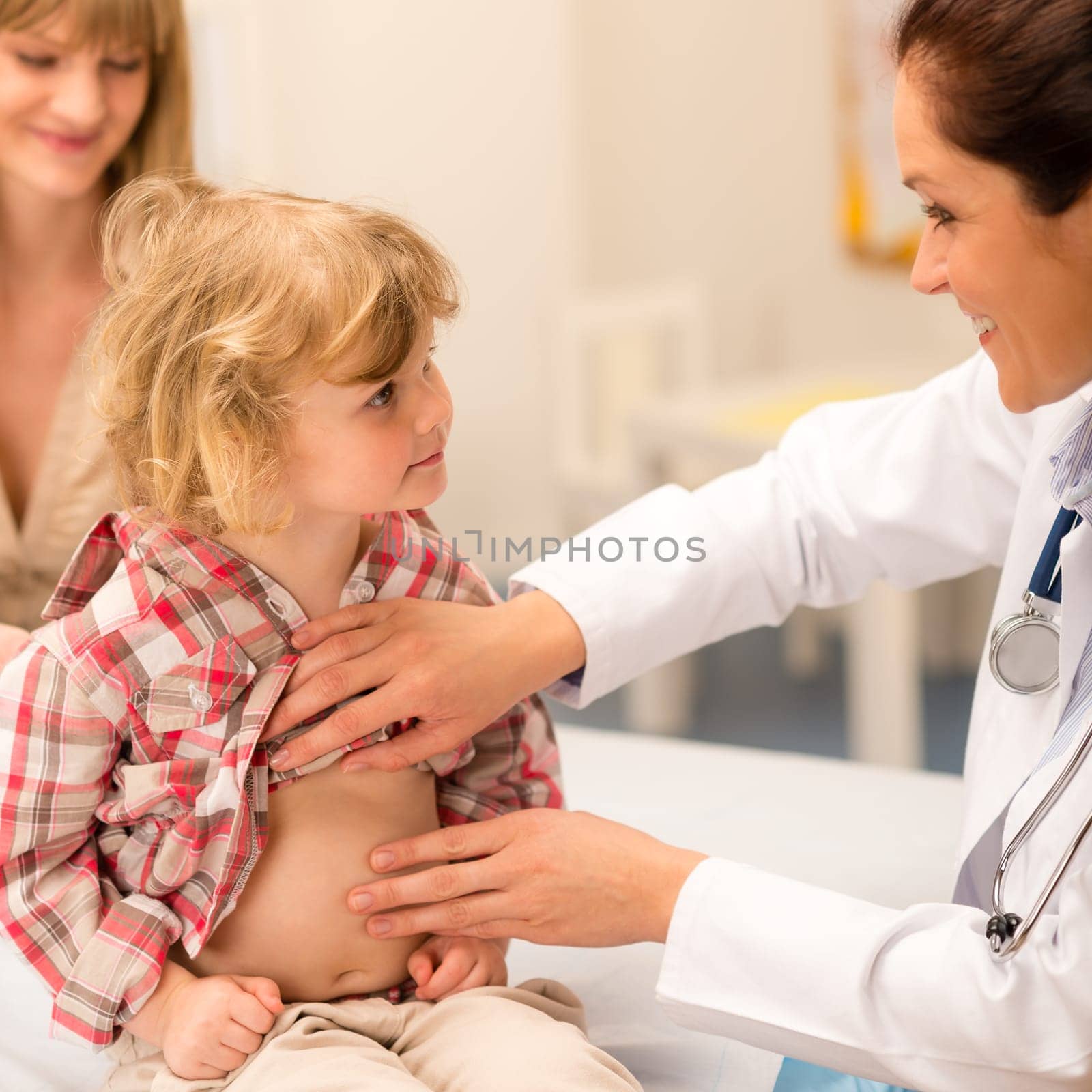 Little girl having tummy examination by pediatrician at medical office