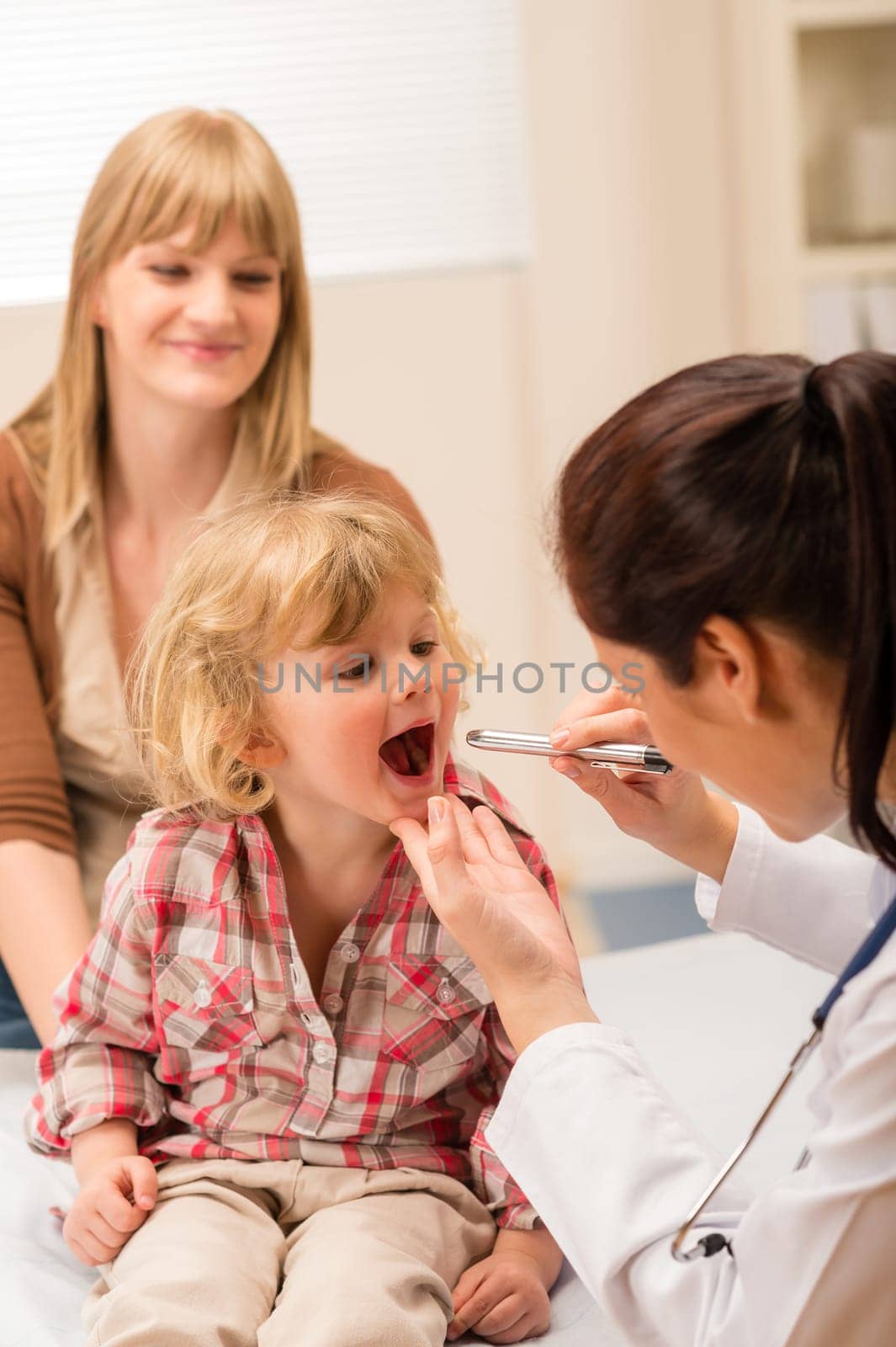 Little girl having throat examination by pediatrician using light pen
