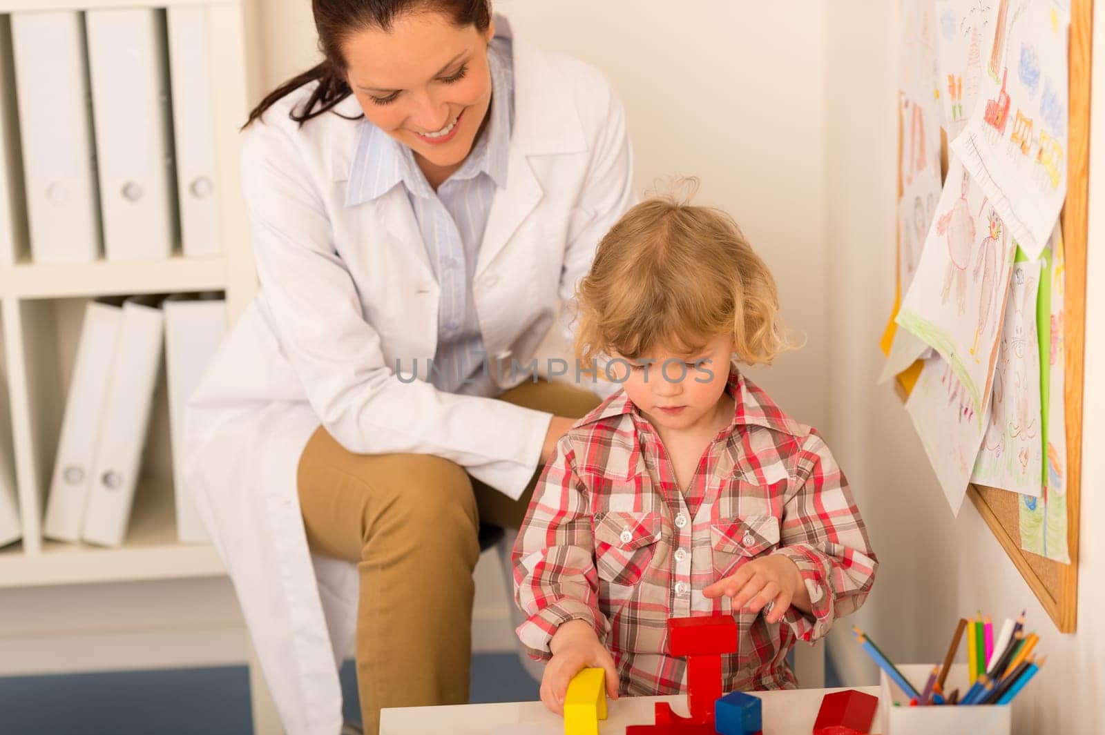 Female pediatrician playing with little girl at medical office