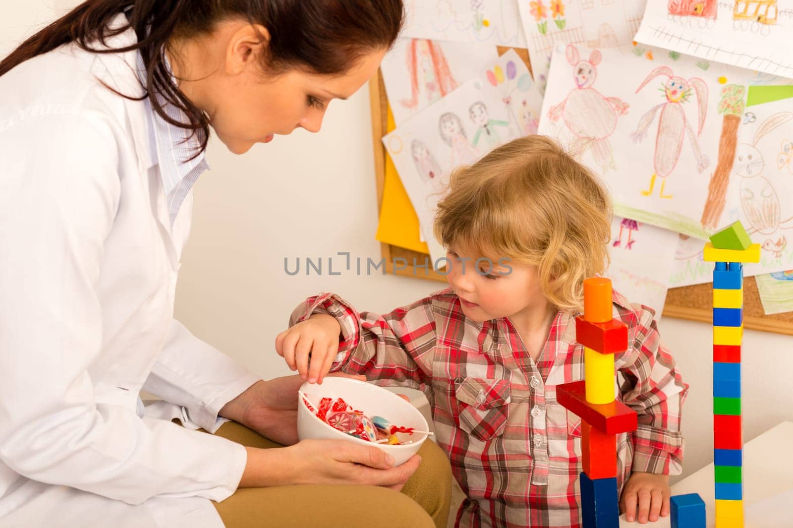 Female pediatrician offering lolly to child reward for bravery