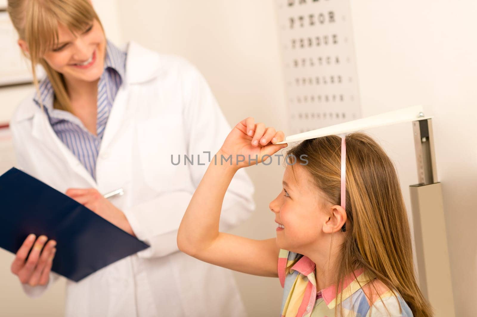 Pediatrician measure height of young girl at medical office