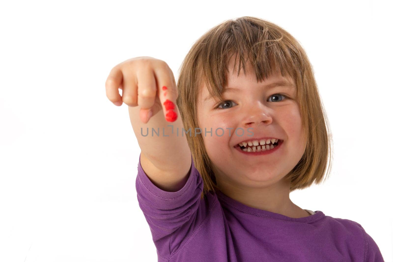 Girl paints with finger paints and shows her red painted finger
