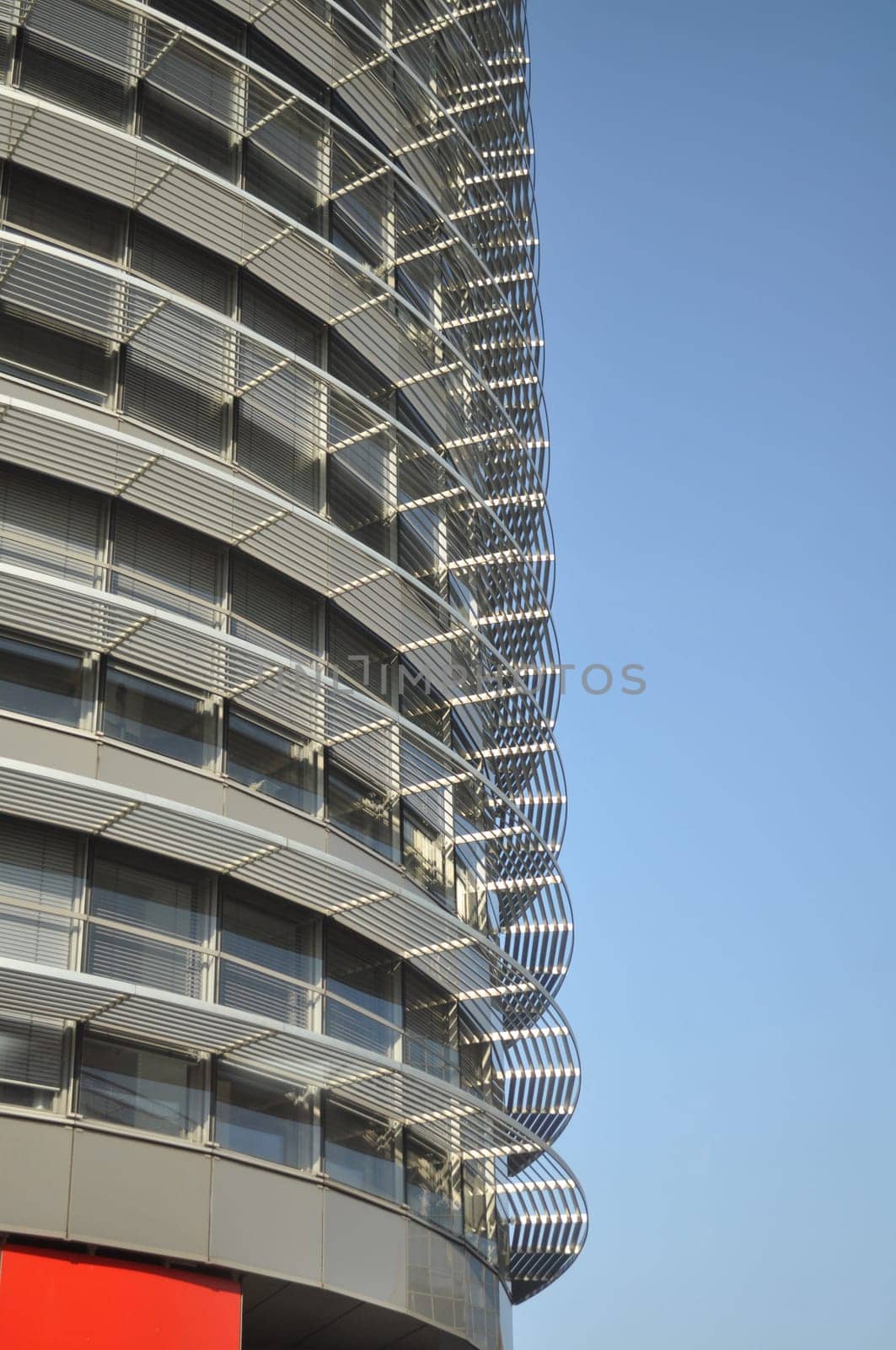 Office building behind the blue sky. The building has a gray glass facade with aluminum panels and visors. Prague, Czech Republic
