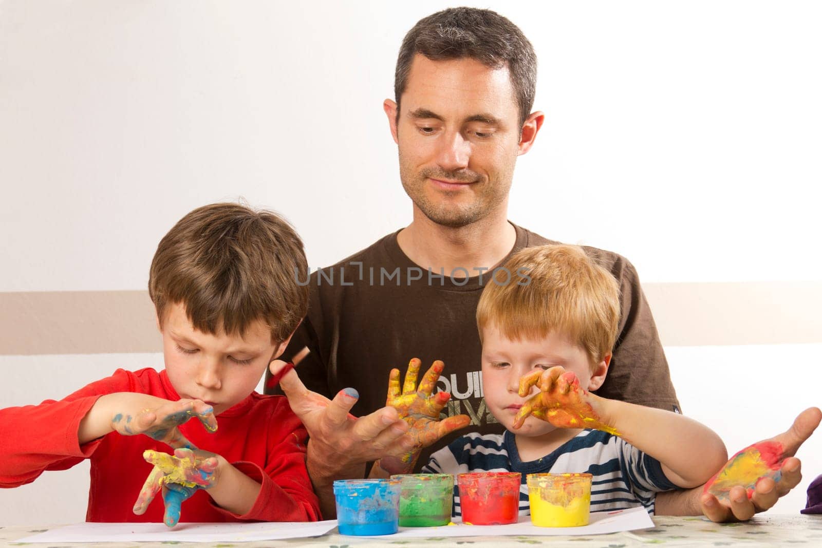 Father painting with his children with finger paint