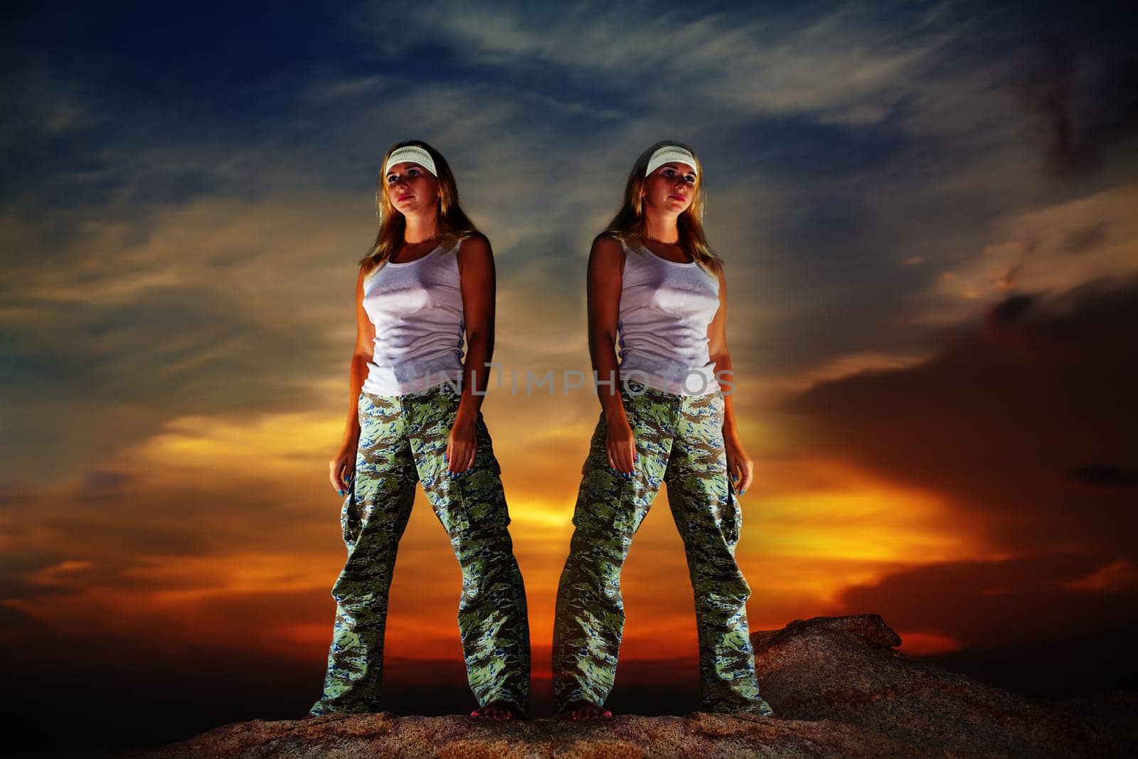 Two military woman staying aon the mountain peak at sunrise time