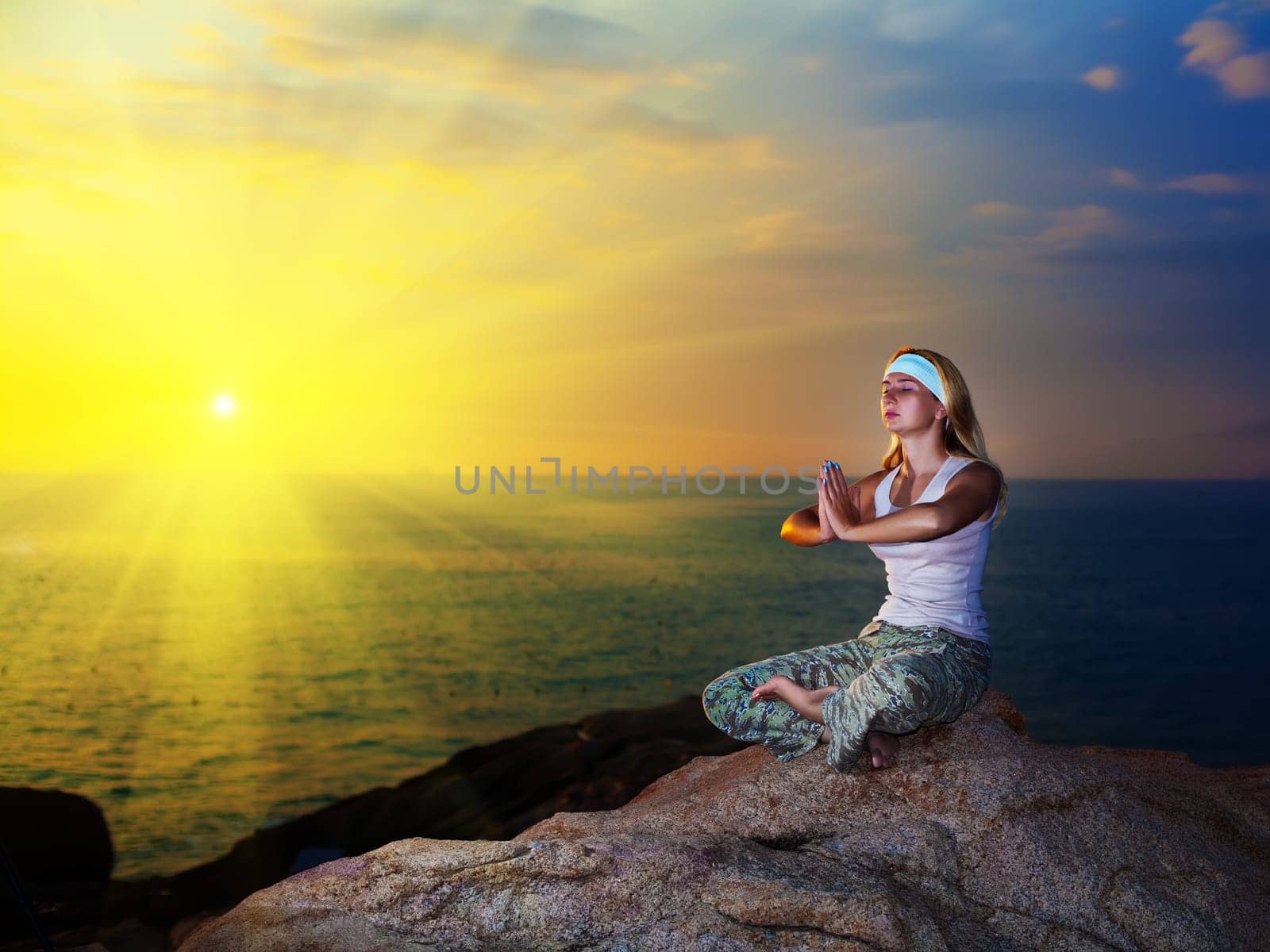 Young woman meditating at sunset time near ocean