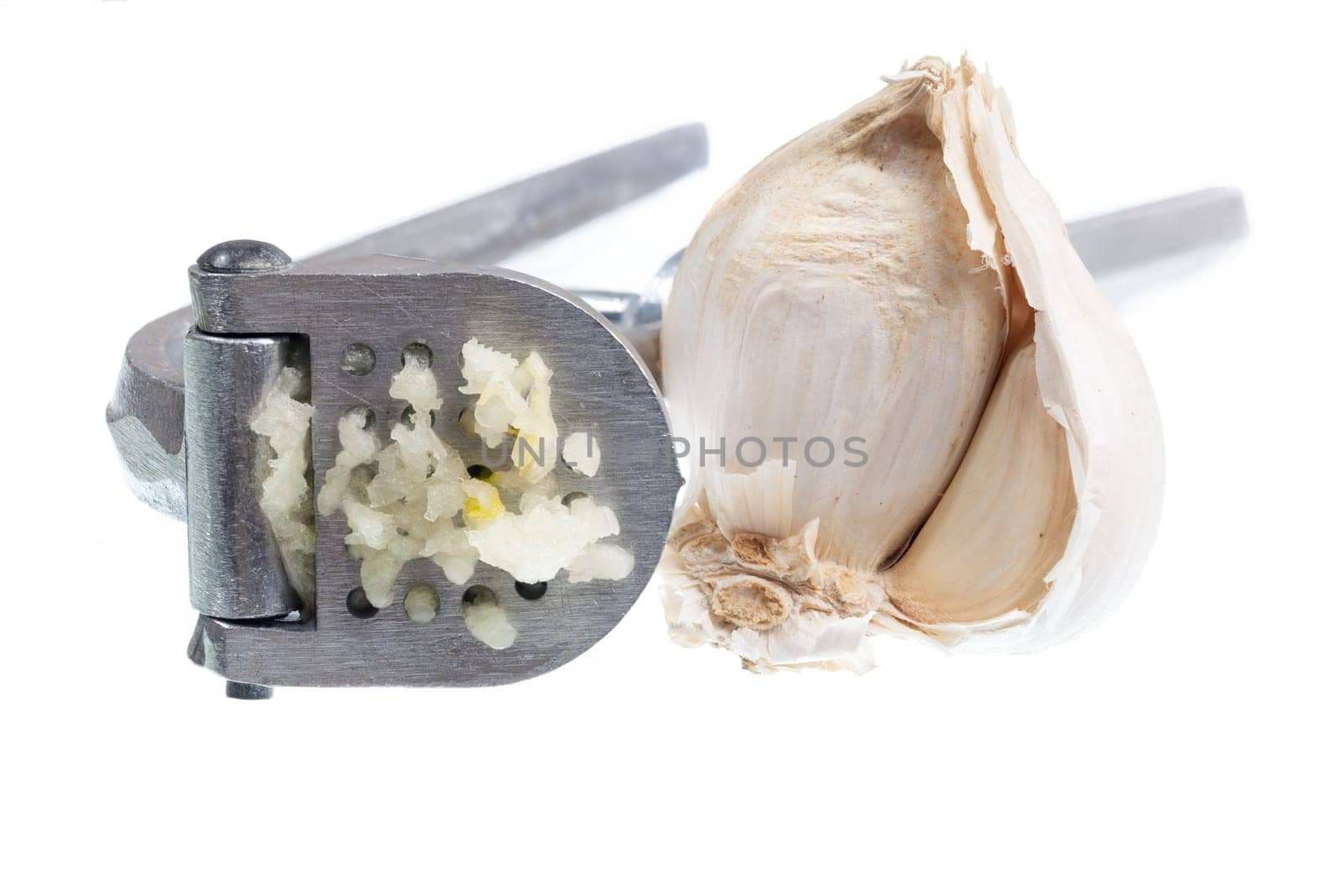 Garlic press and garlic isolated against white in macro shot