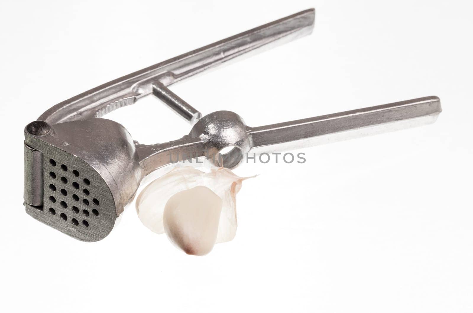 Garlic press and garlic isolated against white in macro shot