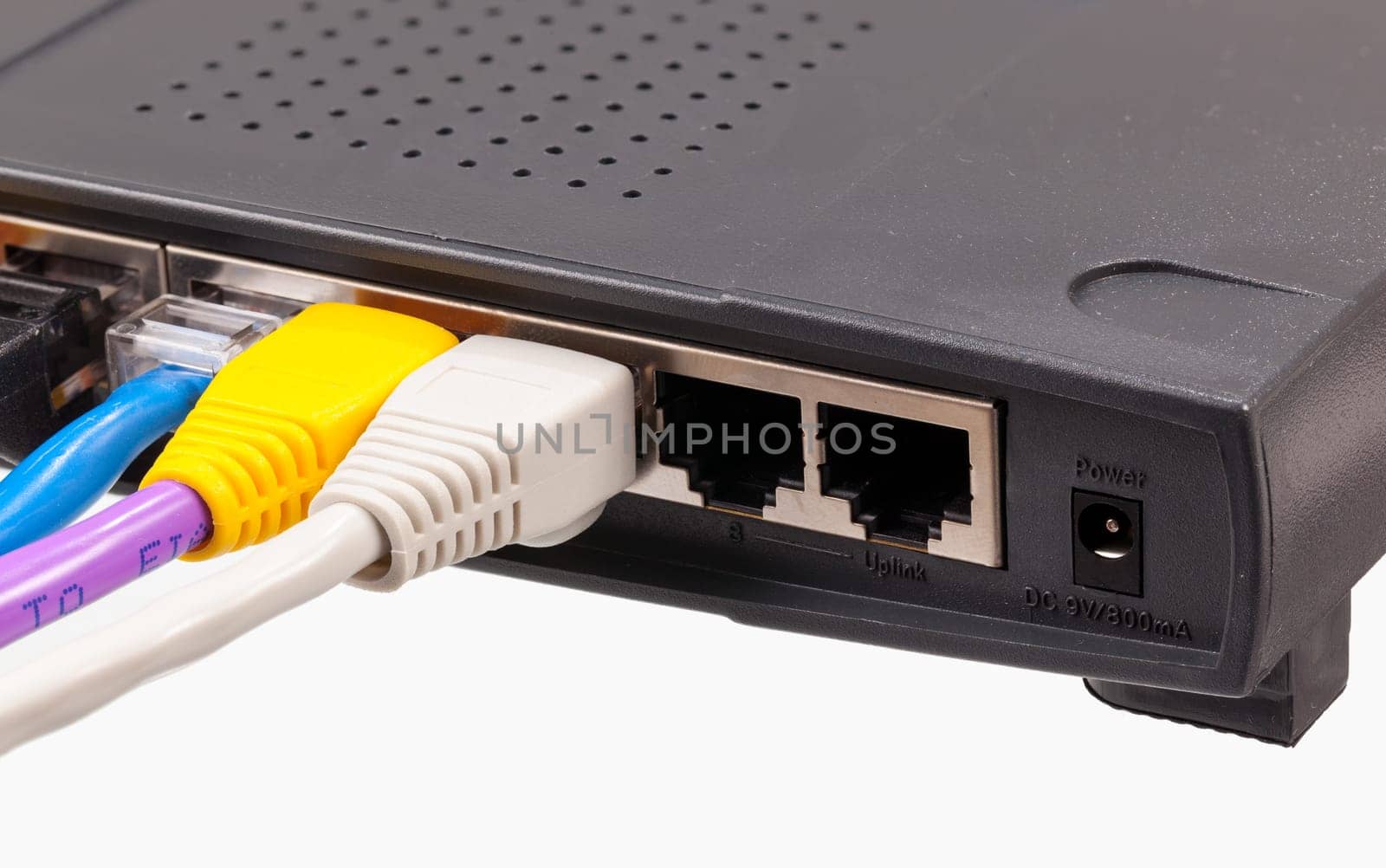 Macro shot of plugs on cat5e cables of many colors isolated against white background plugged into router