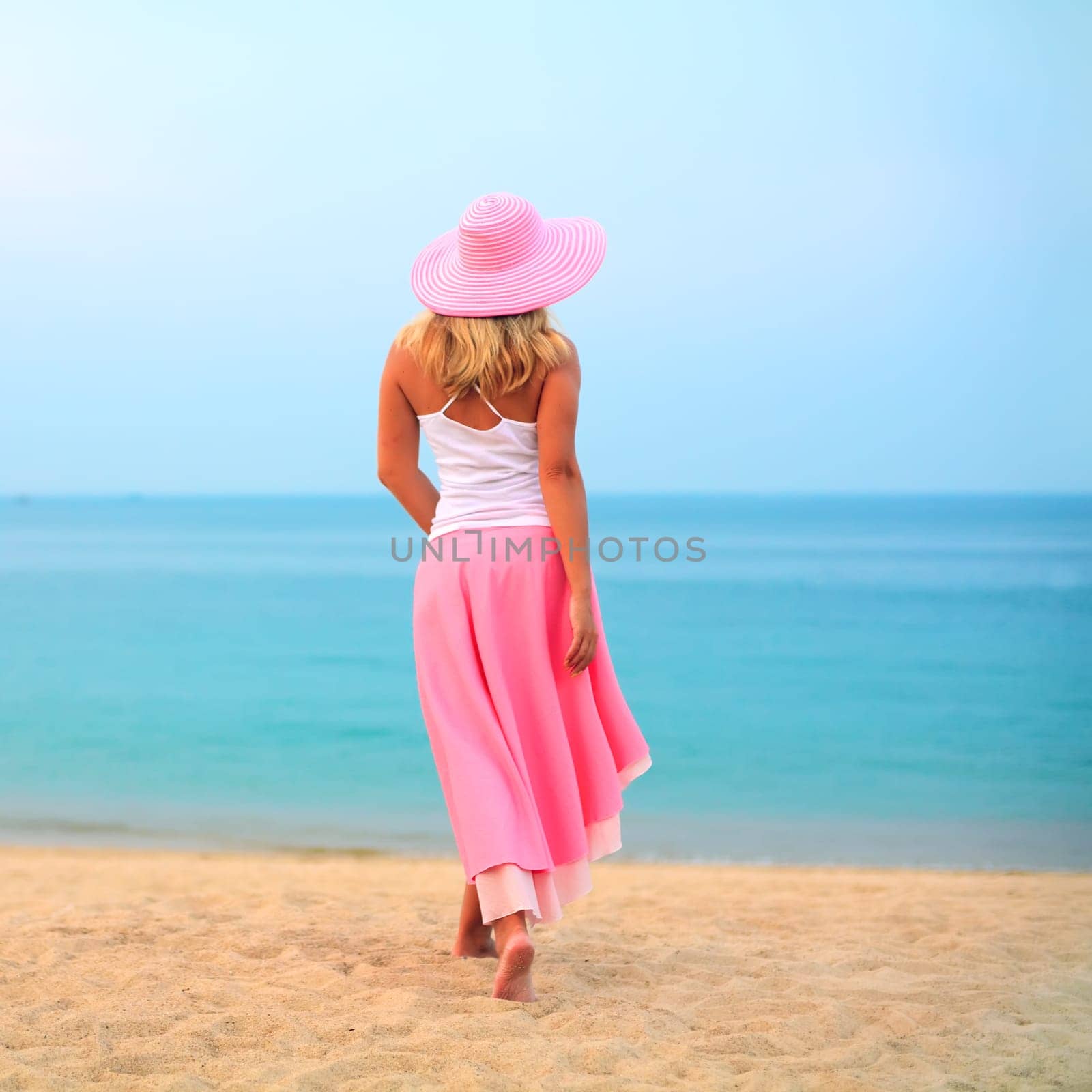 Woman walking near the ocean in pink clothes