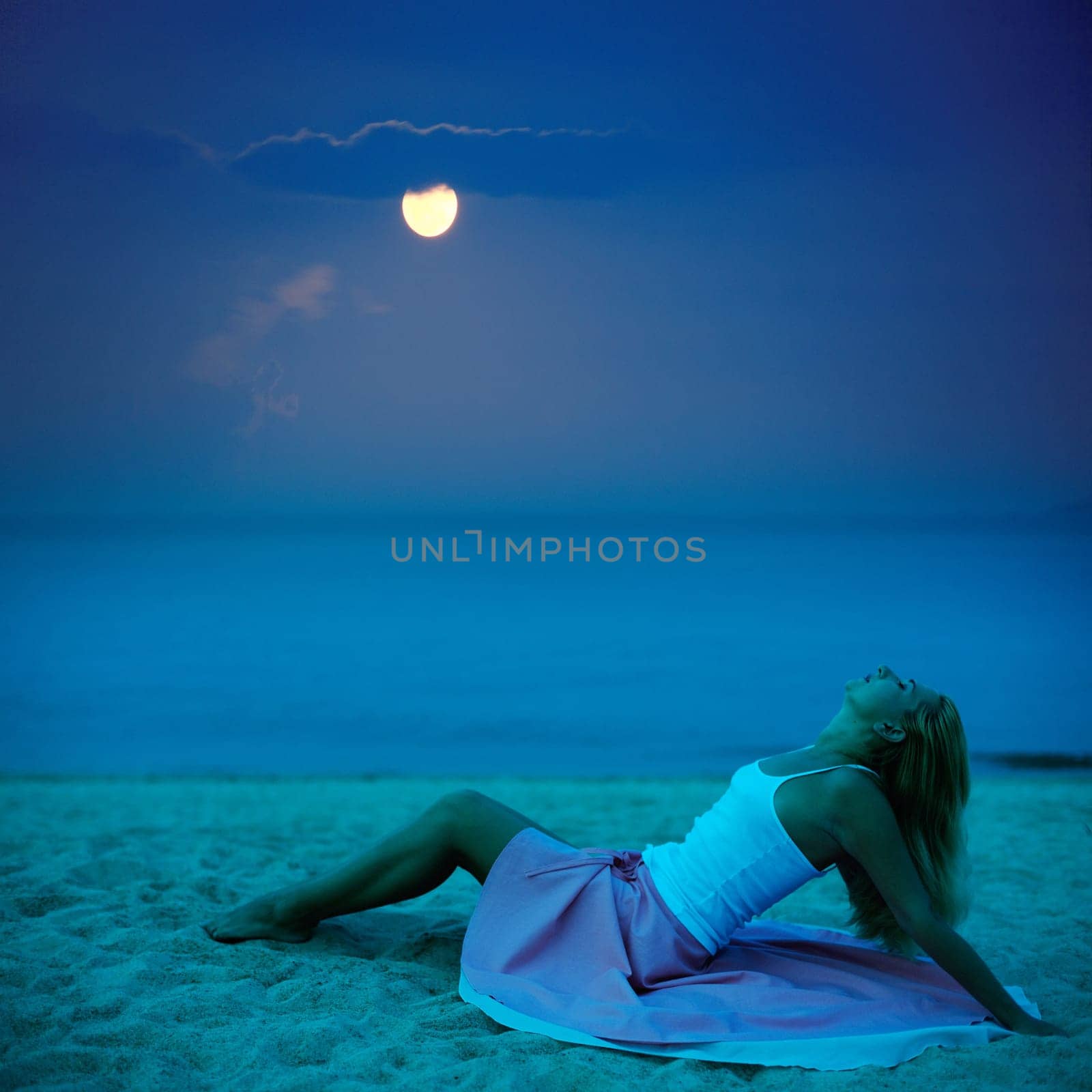 Young beautiful woman posing on the beach at night time