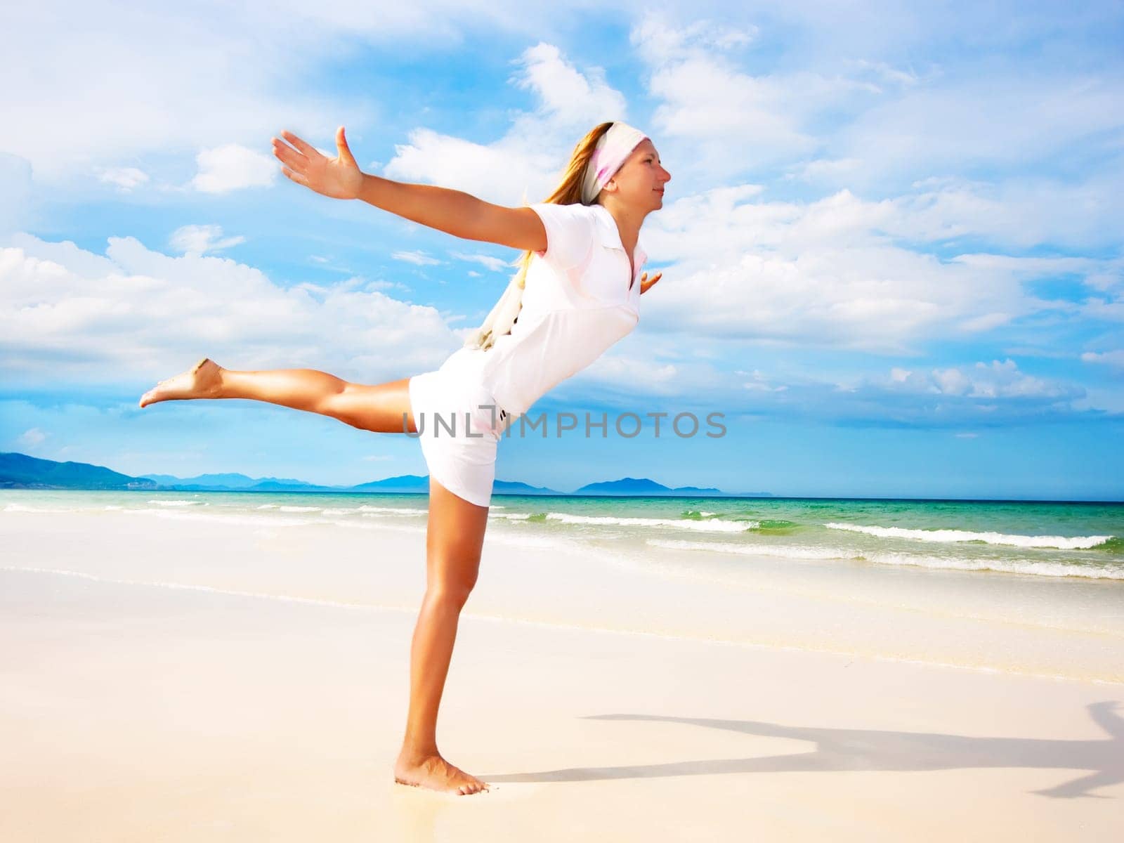 Young woman doing morning exercises close to the ocean
