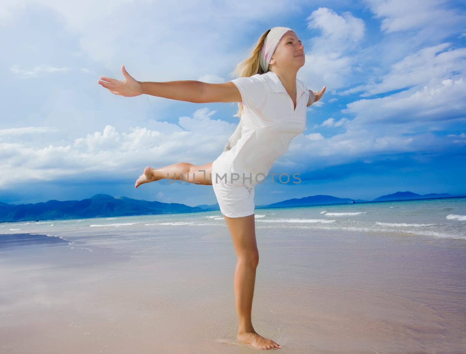 Young woman doing morning exercises close to the ocean