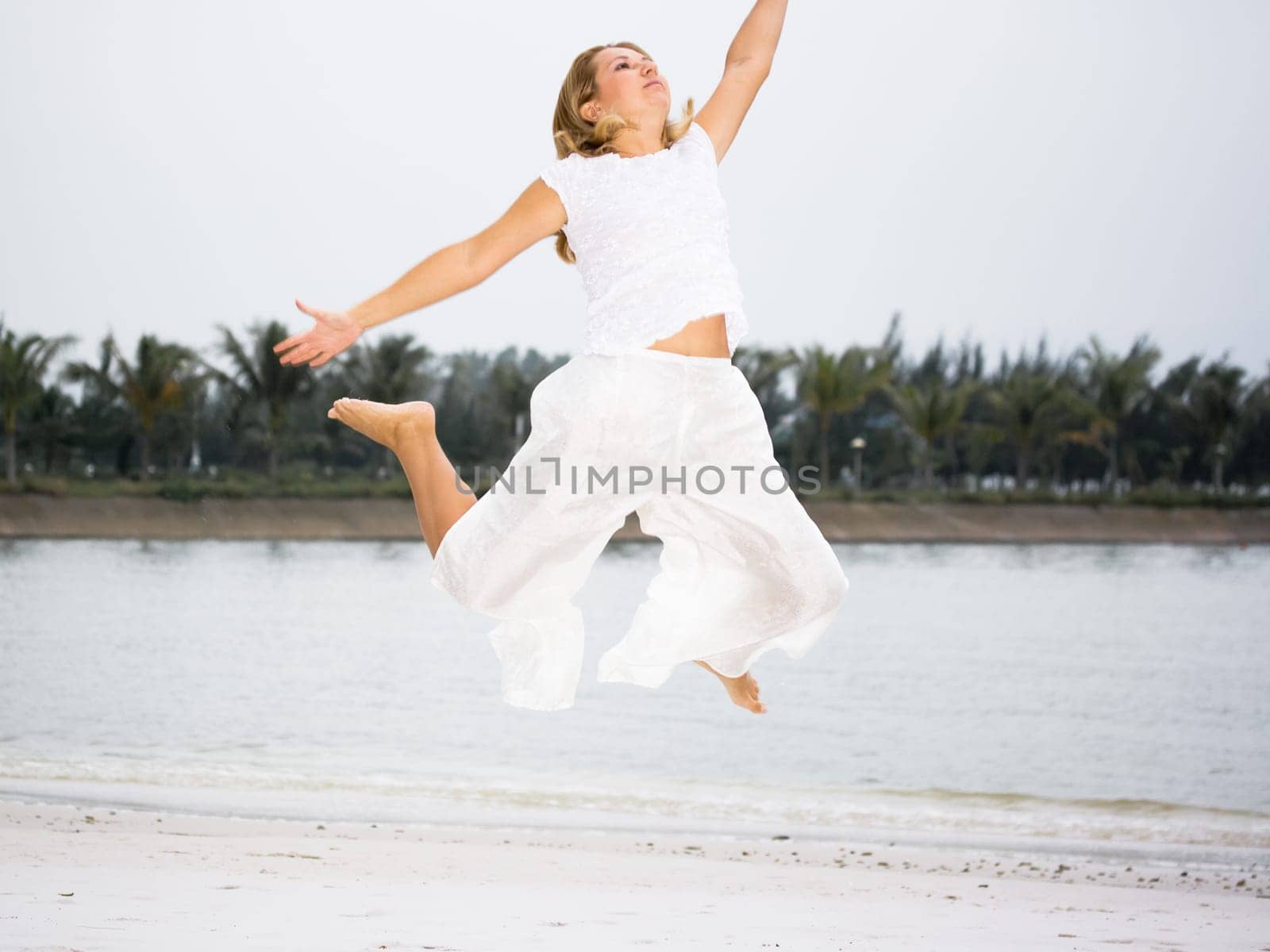 Young woman jumping on the tropical beach