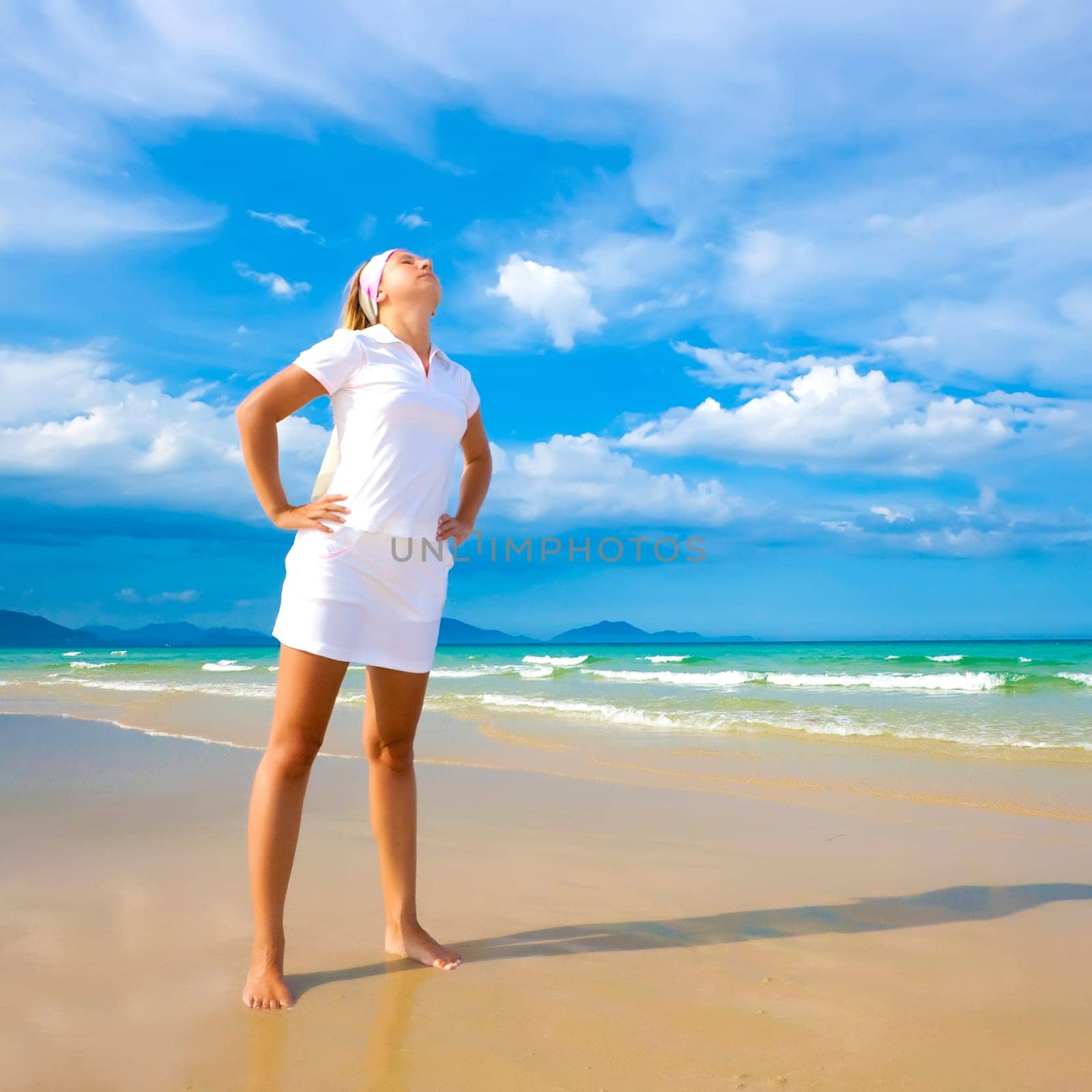 Young woman doing morning exercises close to the ocean