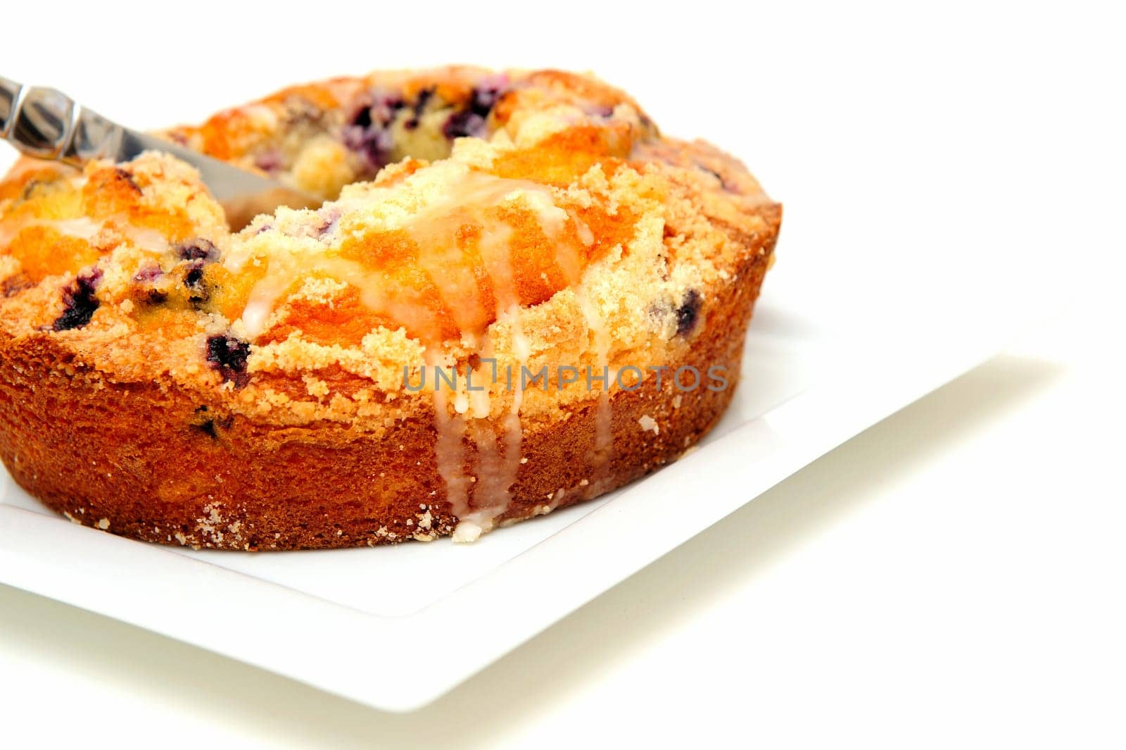 A fresh baked Blueberry Ring Cake served on a square white plate with a light colored background