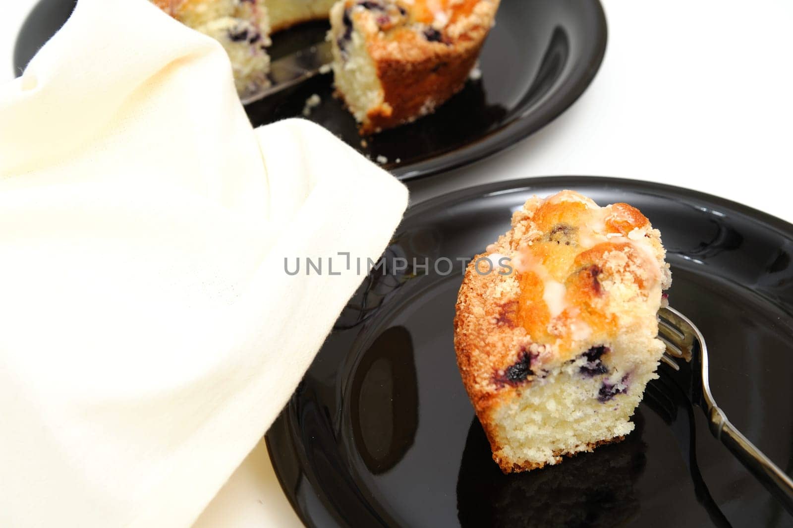 Slice of fresh baked Blueberry Ring Cake served on a black plate with a light colored background