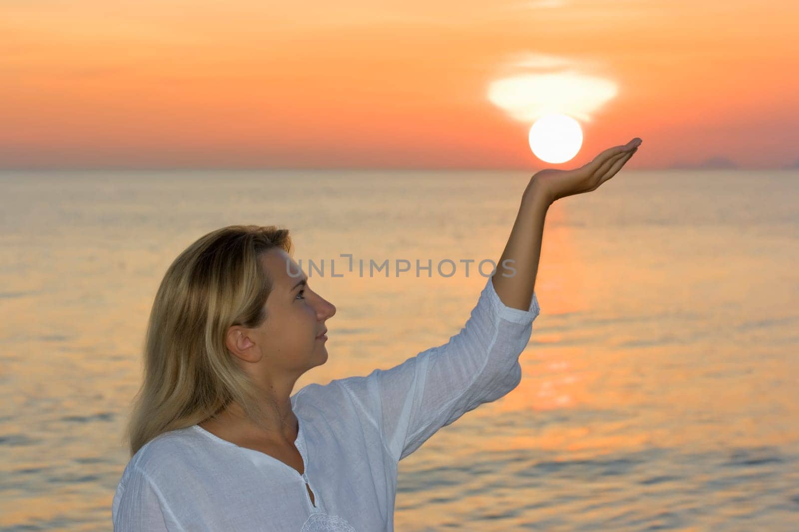Young woman on the tropical beach at sunrise time. Sun in her hand