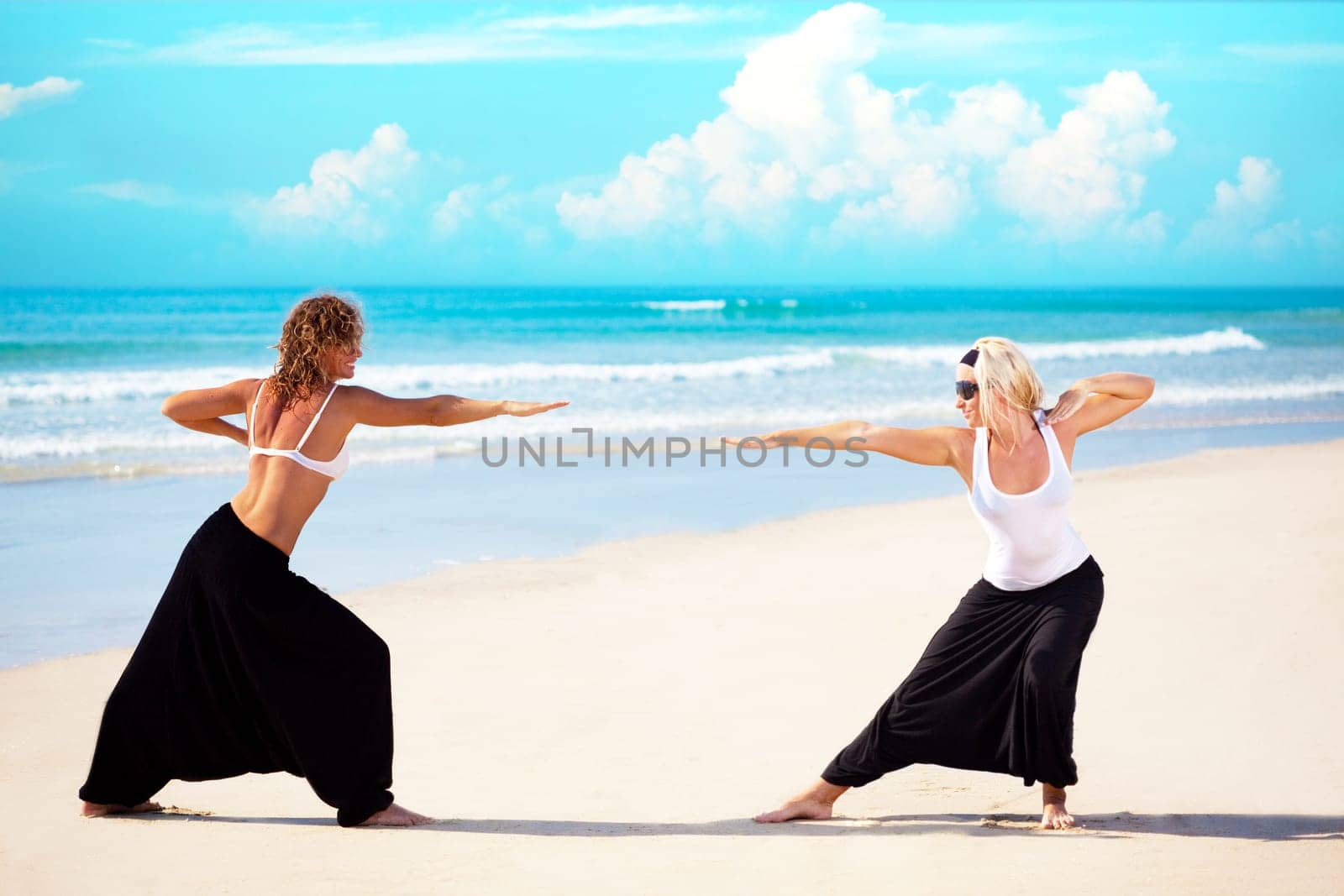 Two beautiful young woman training near the ocean