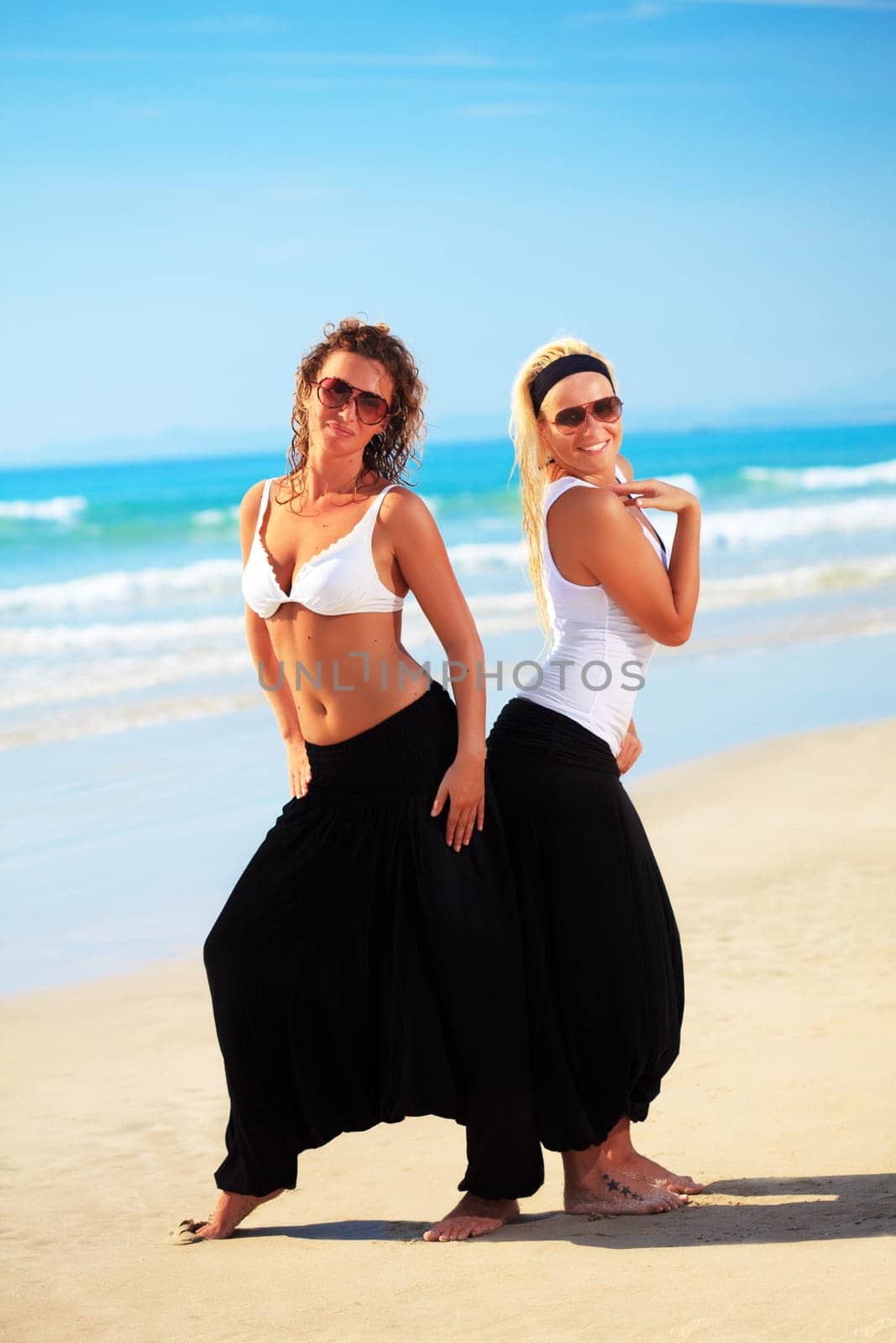 Two young beautiful woman in cambodian pants near the ocean