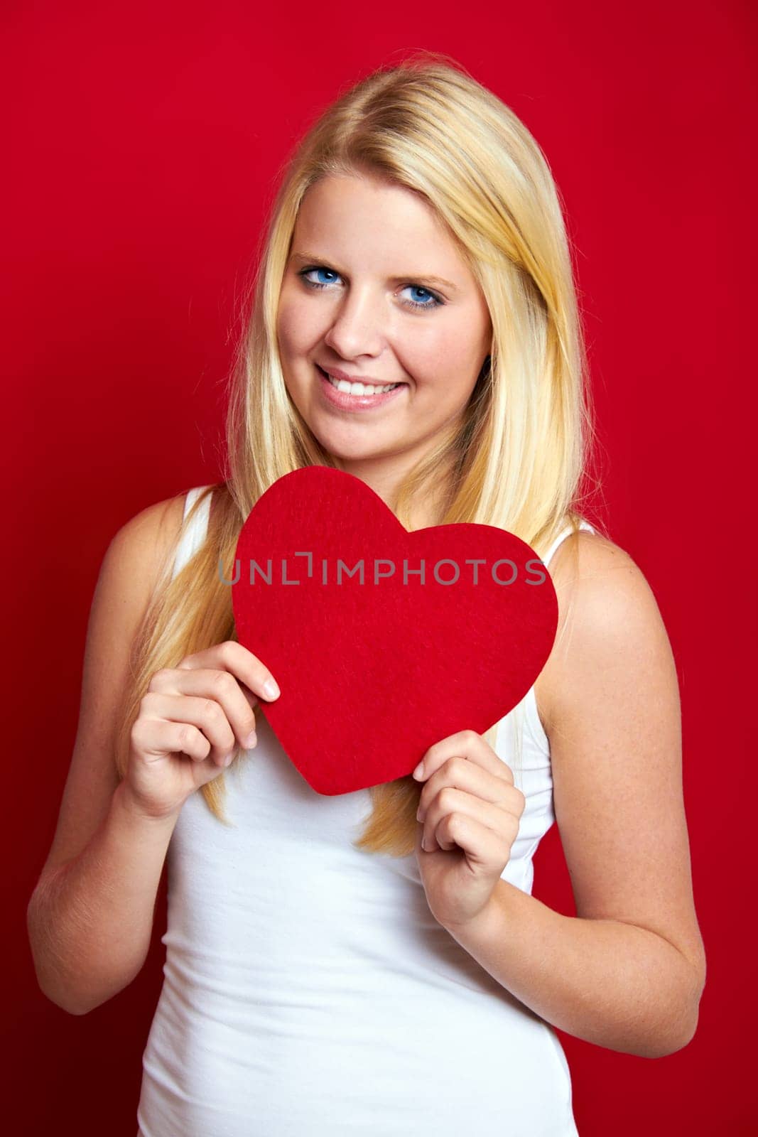 Young blonde woman with red heart in hands