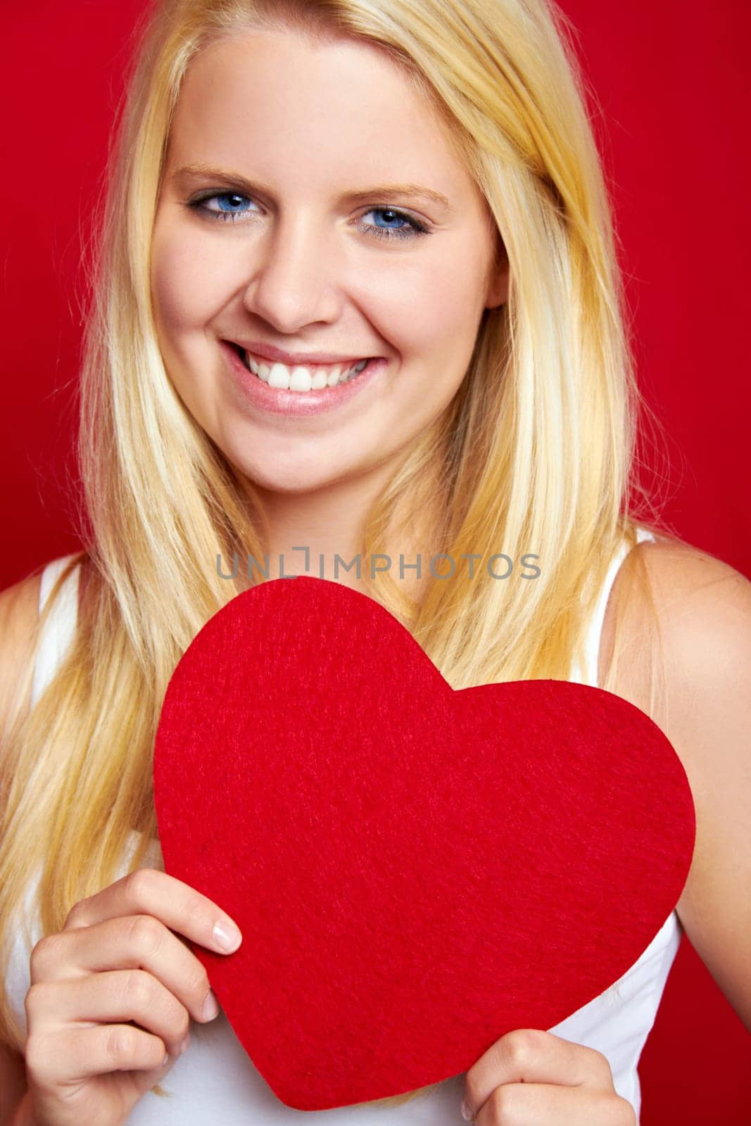 Young blonde woman with red heart in hands