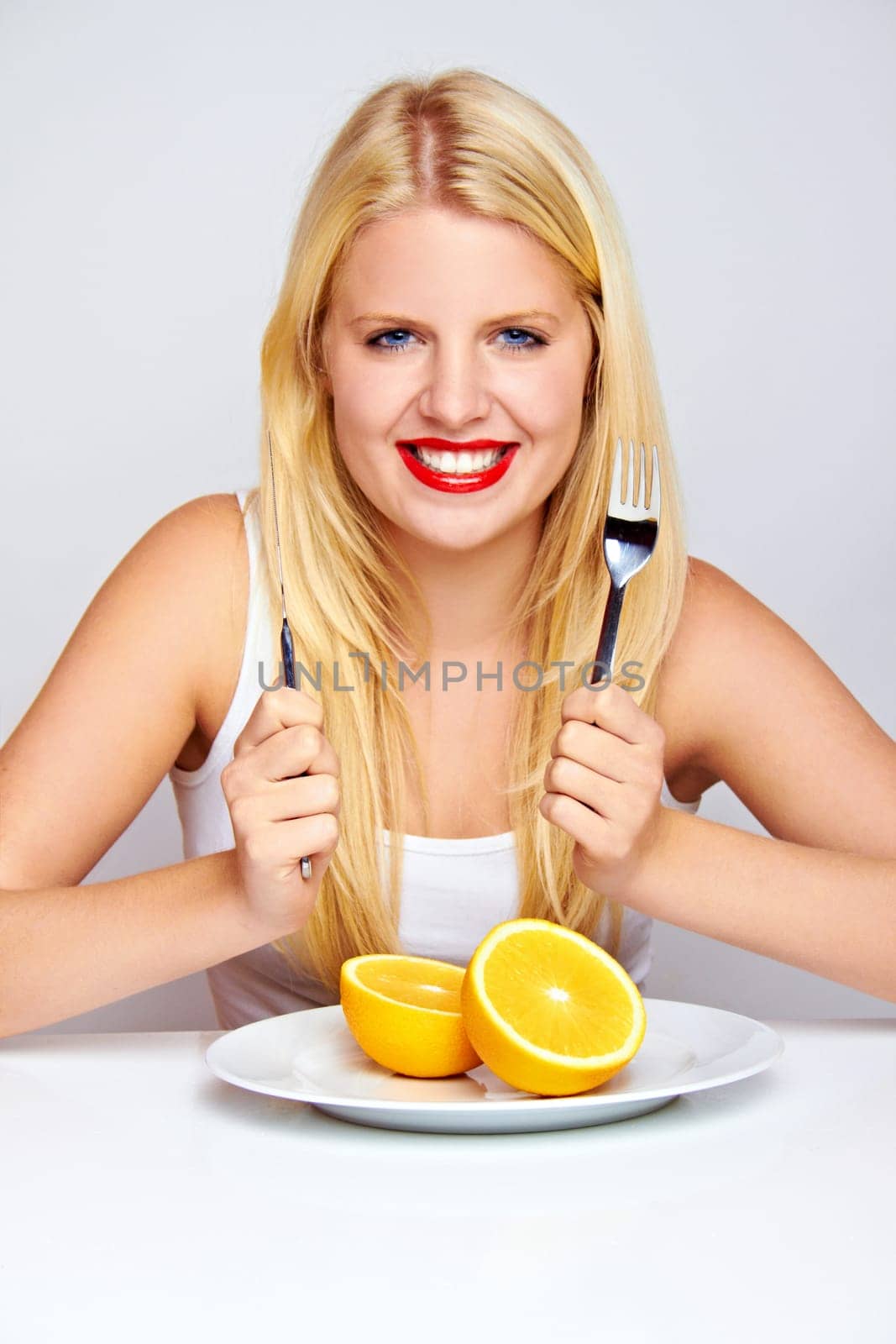 Happy young woman eating fruit with cutlery