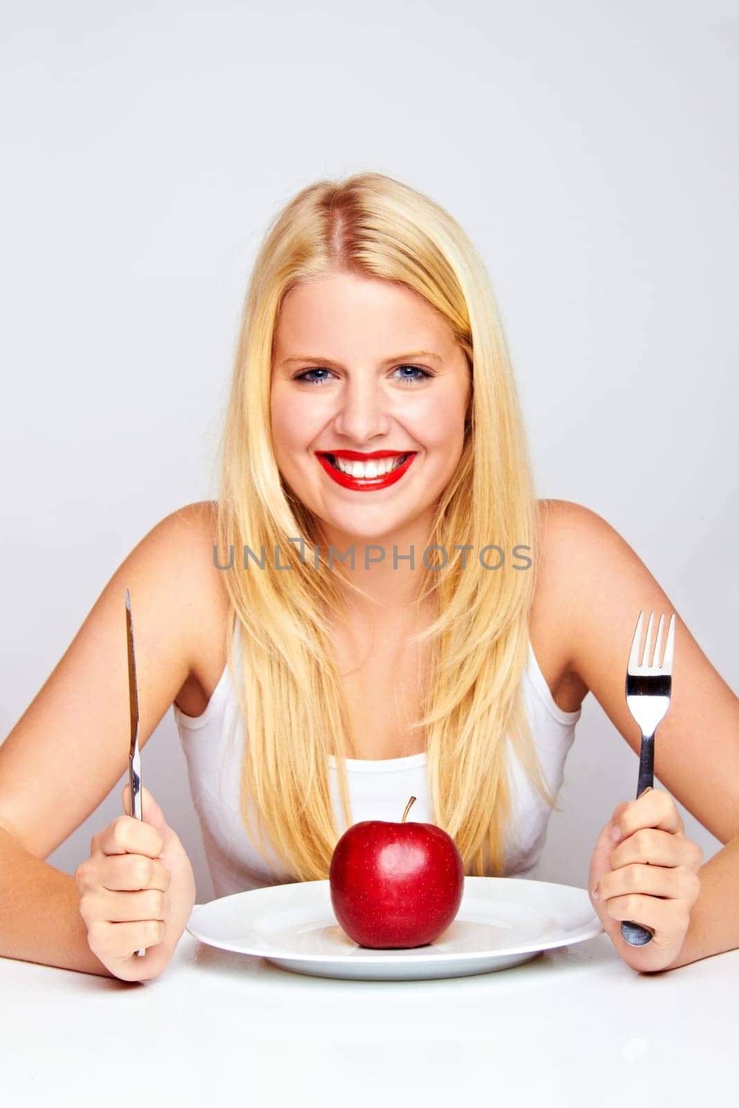 Happy young woman eating fruit with cutlery