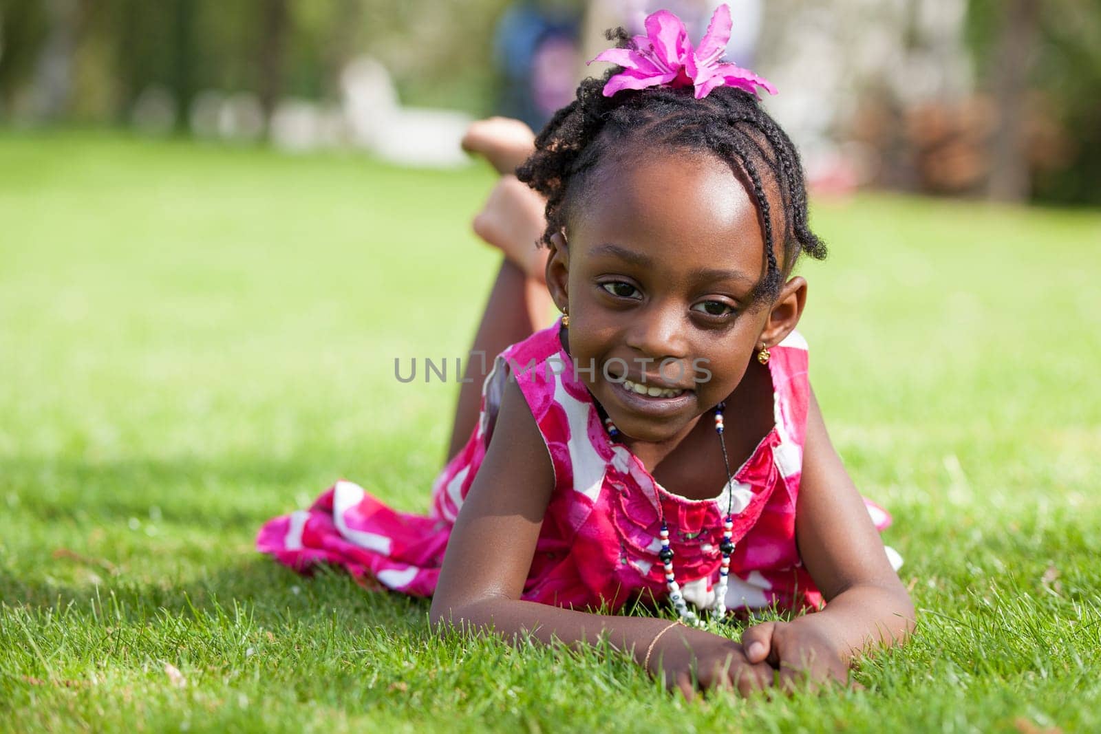 Outdoor portrait  of a cute little African american girl lying down on the grass