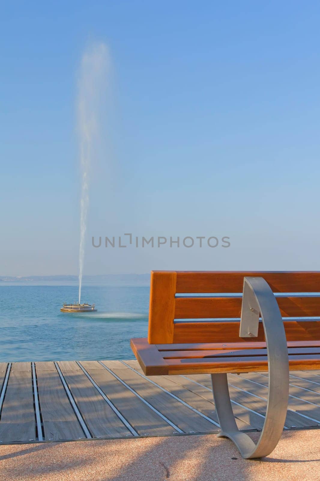 Modern benches along the coastline of Lake Garda. Benches and a fountain in the lake. (Bardolino,Italy)