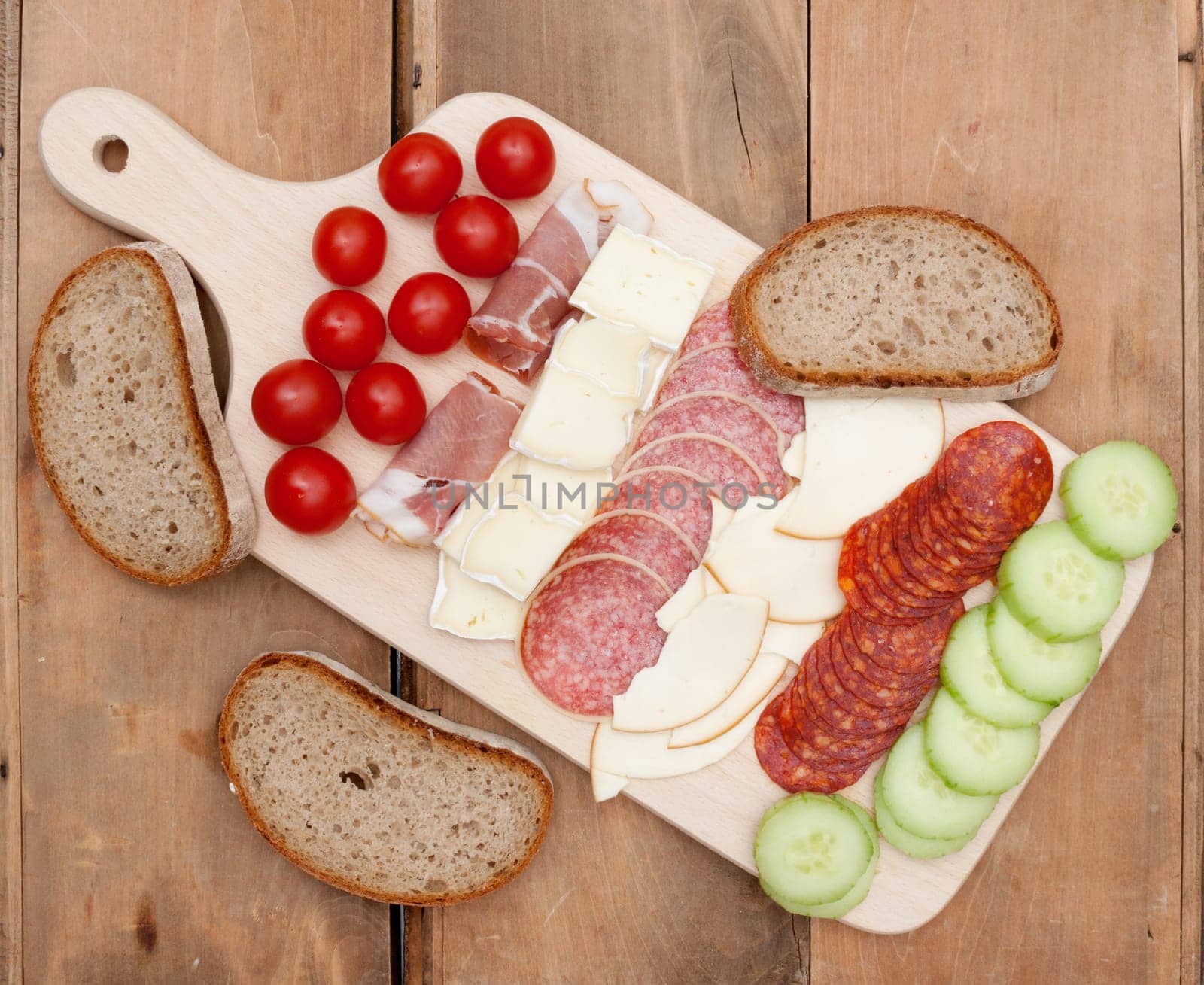 Snack - Salami, Cheese, Vegetables and Bread on Wooden Chopping Board