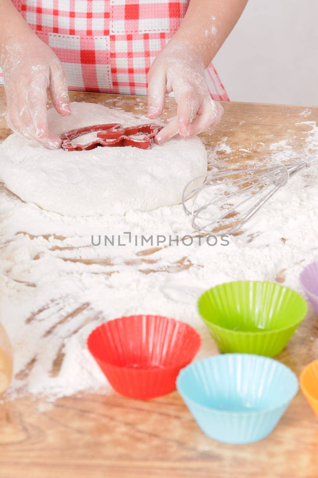 a little girl is cooking the dough for making biscuits
