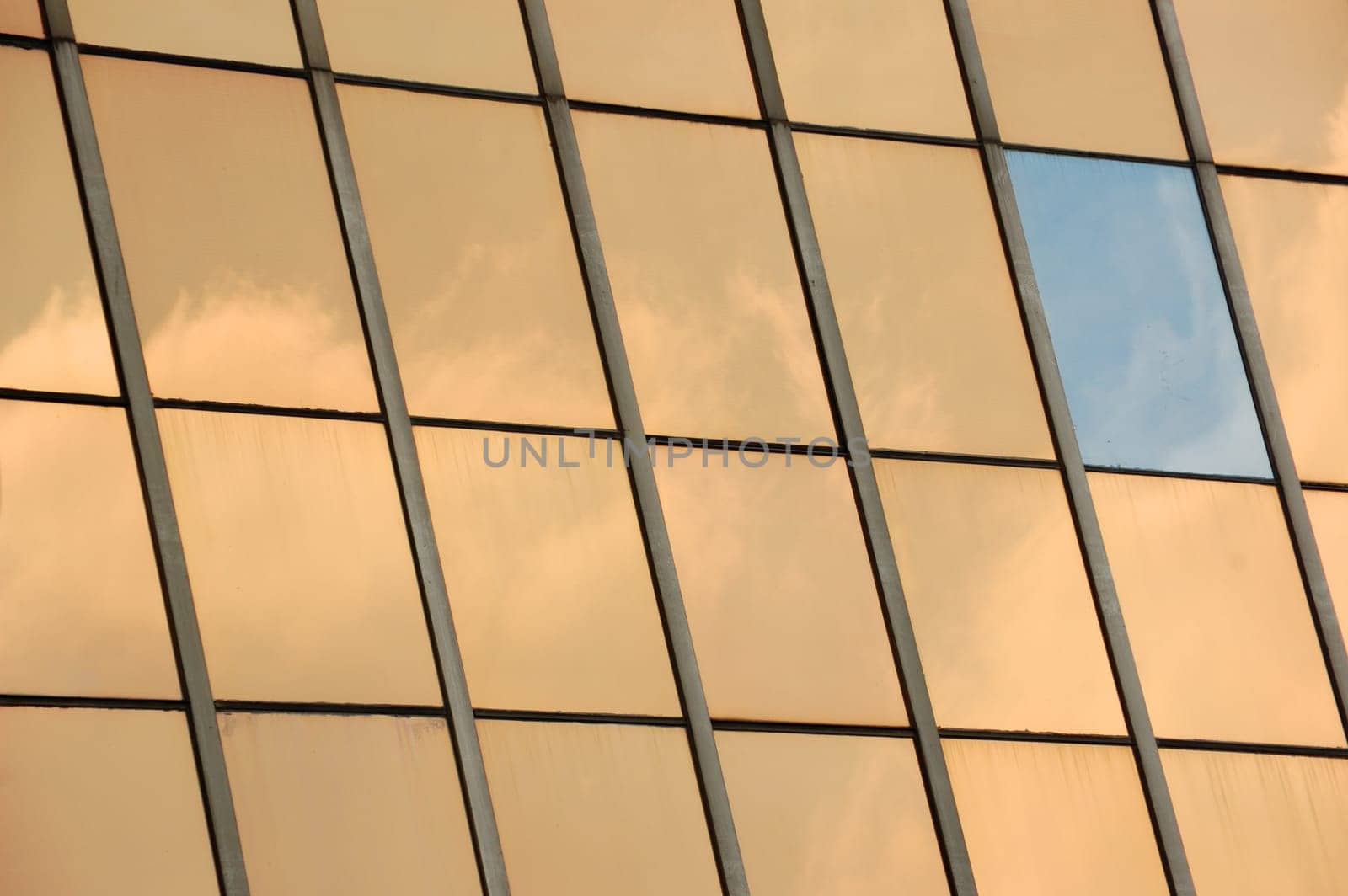 Sky reflected on glass facade panel of a modern building. Abstract background.