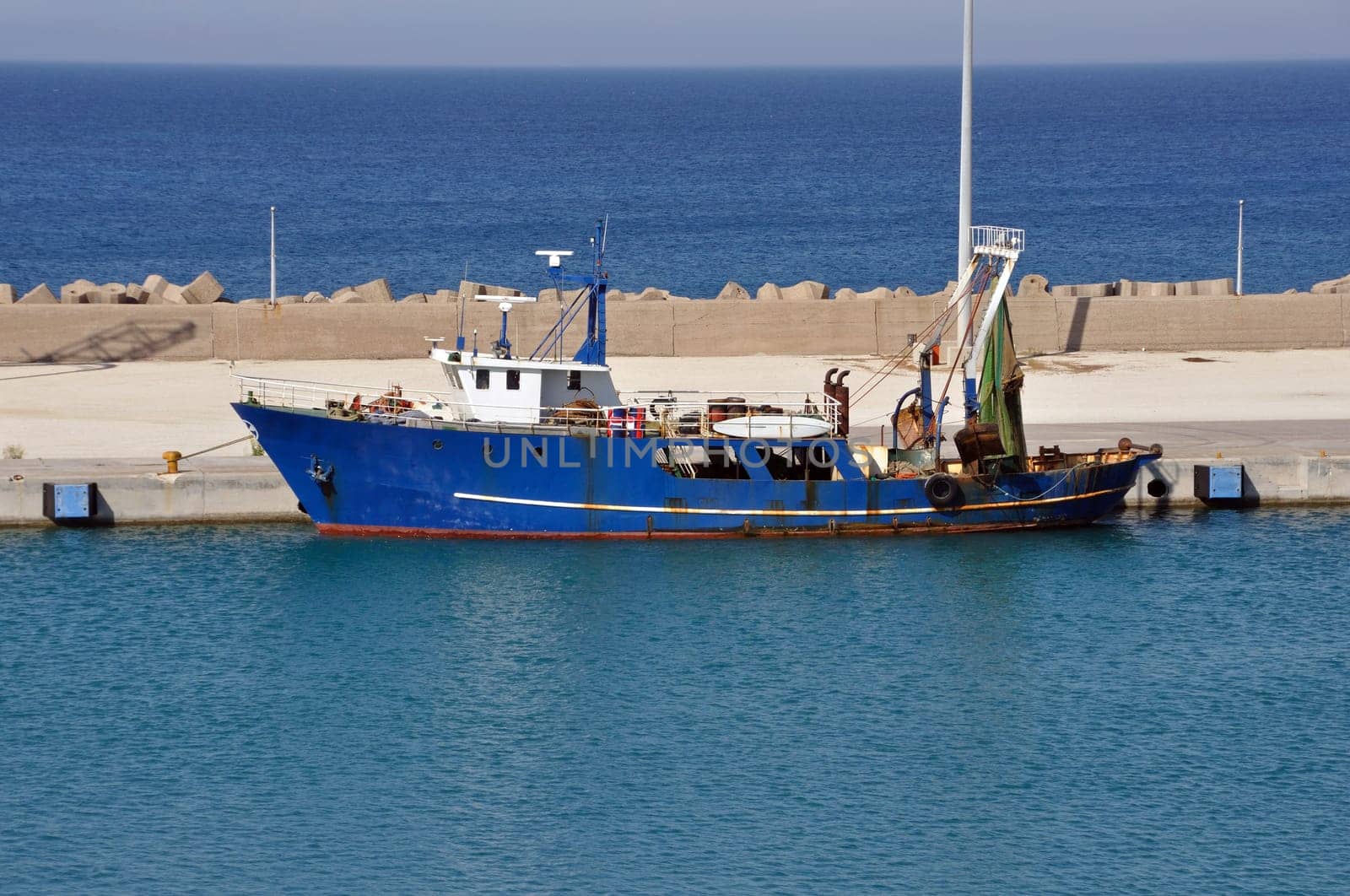 Fishing trawler in port. Rusty dragger ship tied to shore.